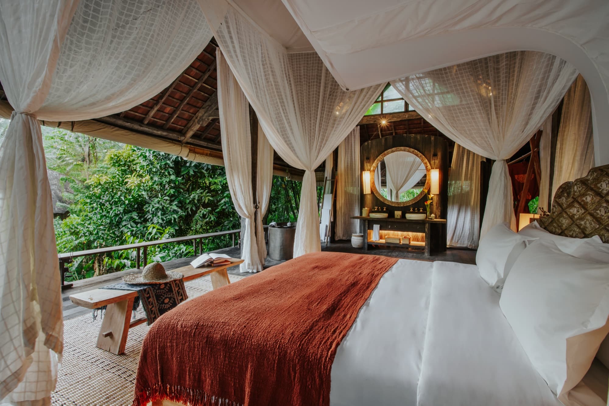 Open-air villa bedroom with canopy bed and jungle views at Buahan