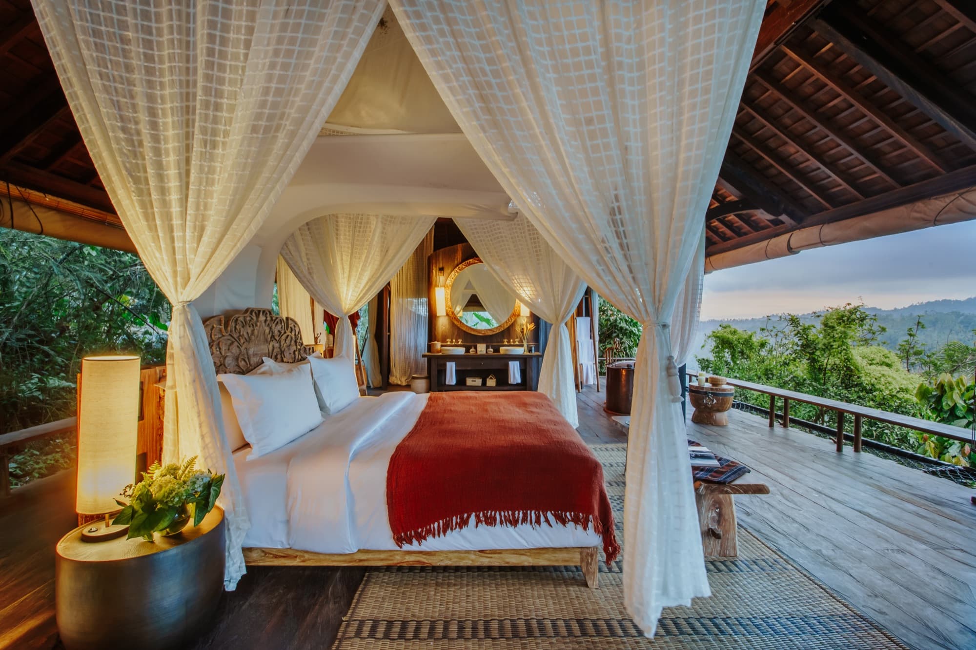 Open-air bedroom with canopy bed and no walls or doors — jungle immersion