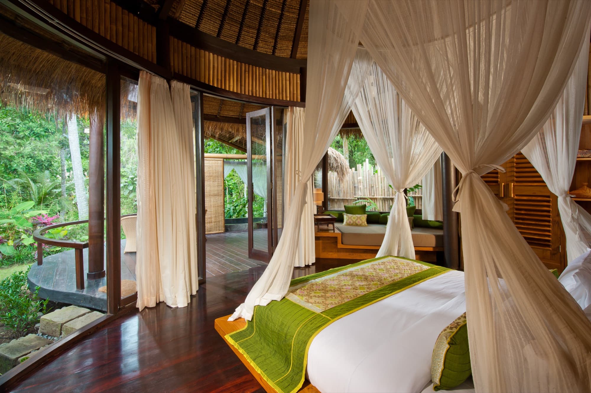 Bedroom under thatched roof opening onto the jungle