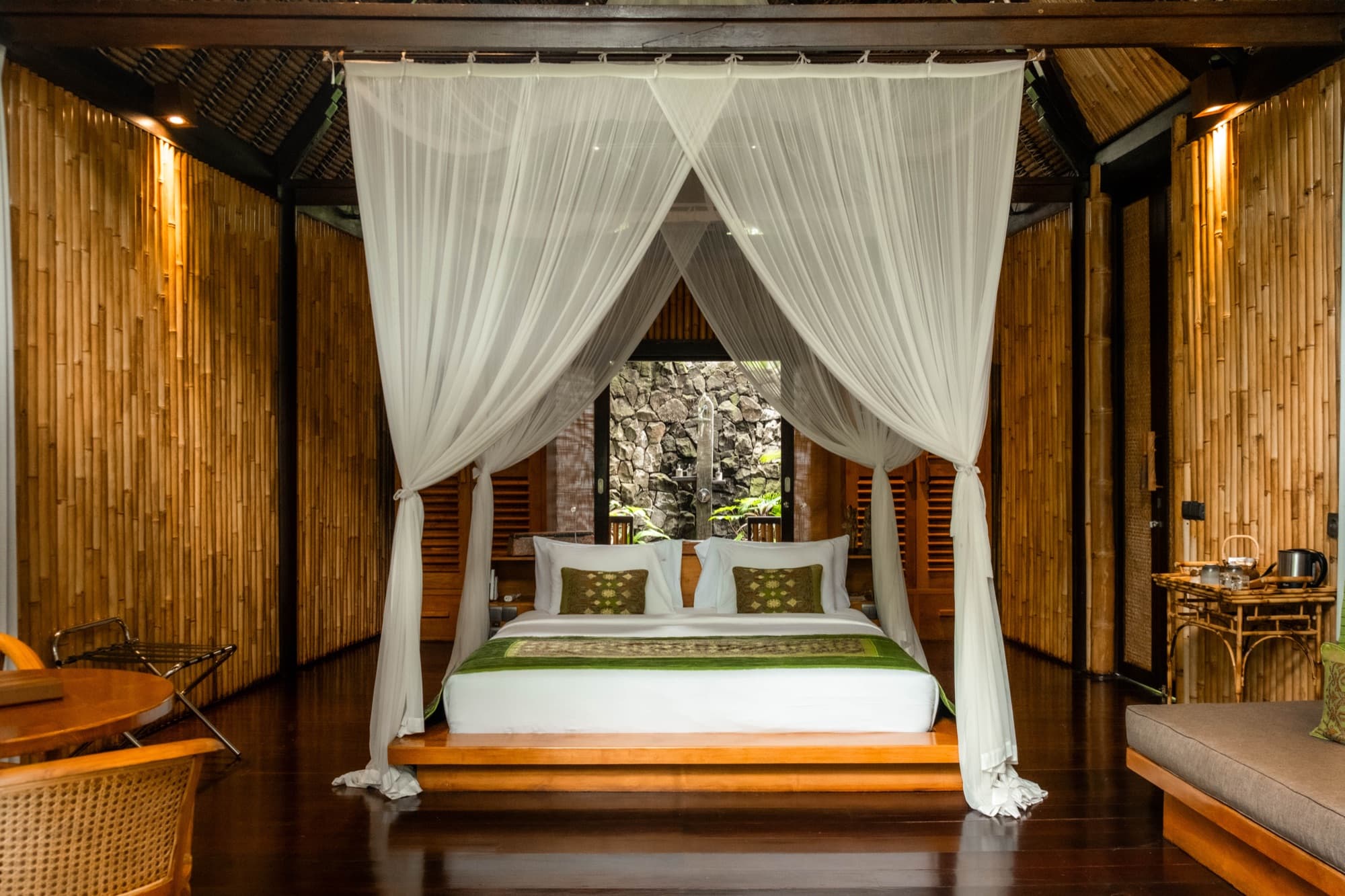 Bedroom with canopy bed framed by bamboo walls