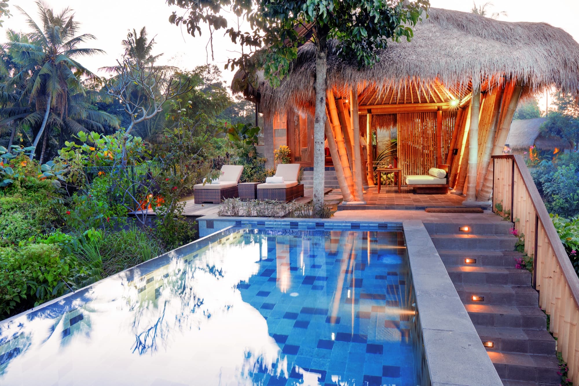 Private suite pool with blue tile and bamboo pavilion at dusk