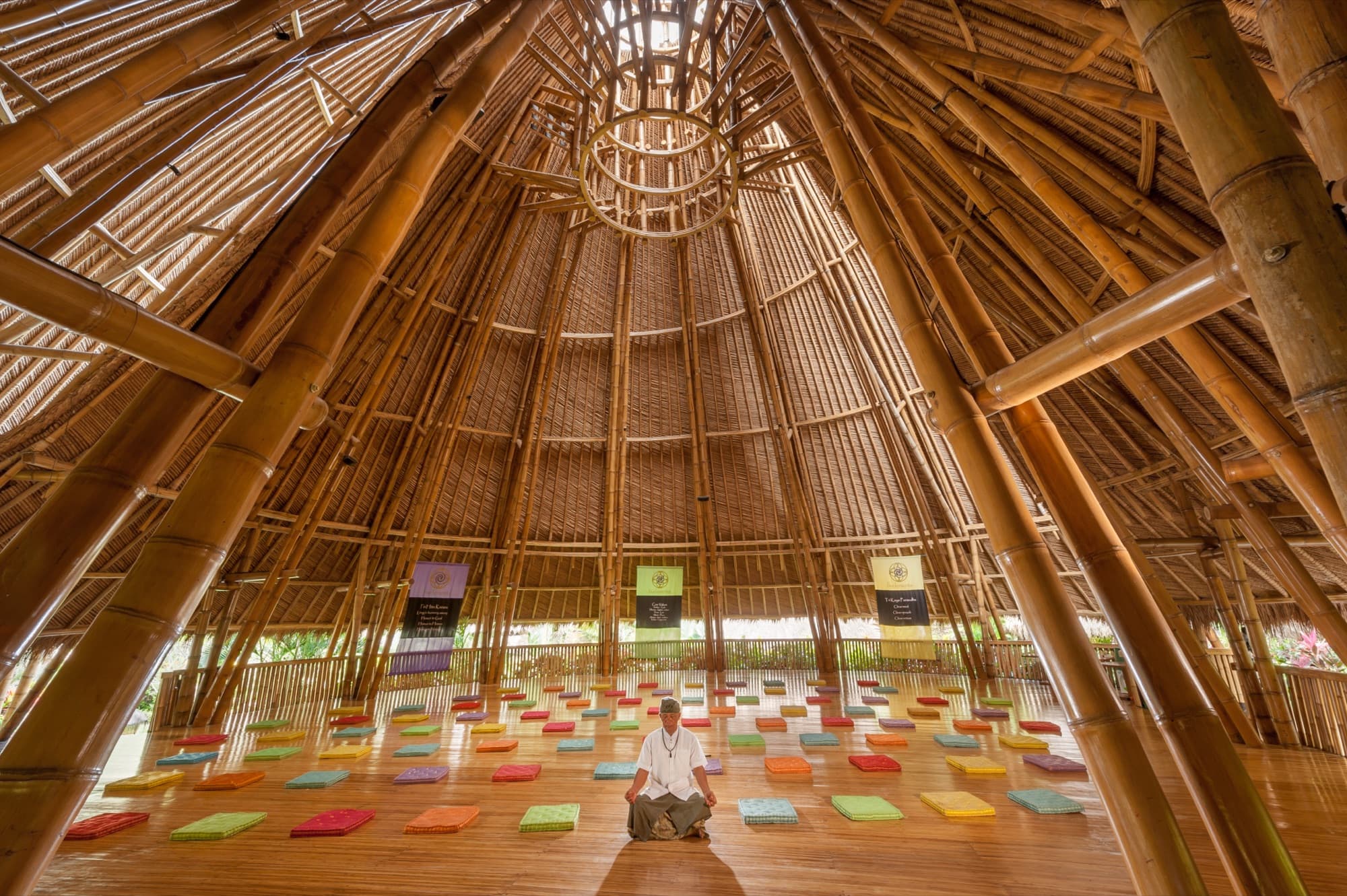 Yoga shala interior with meditator and coloured floor cushions