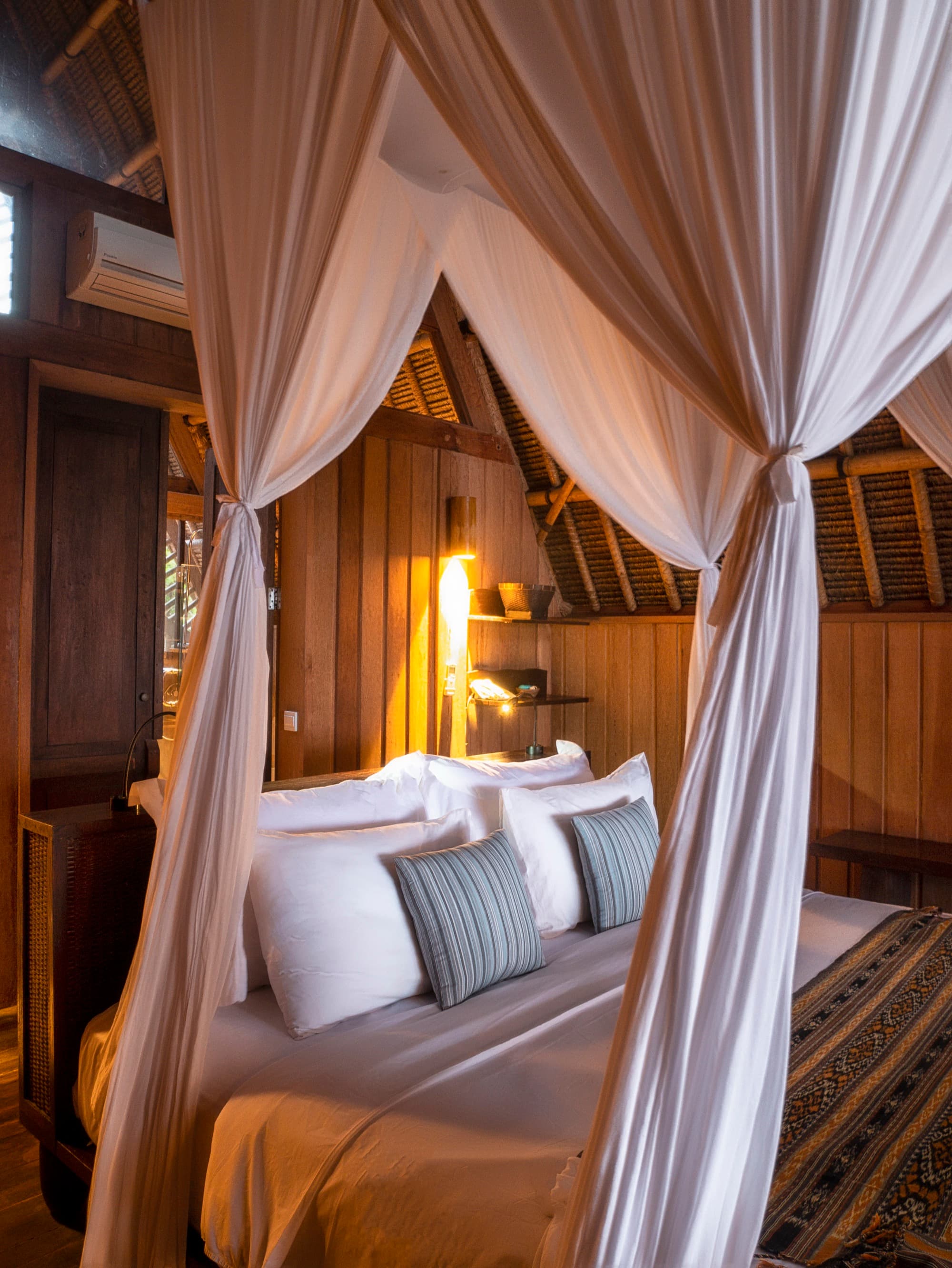 Lodge bedroom interior with bamboo structure and glimpse of the Indian Ocean through the door