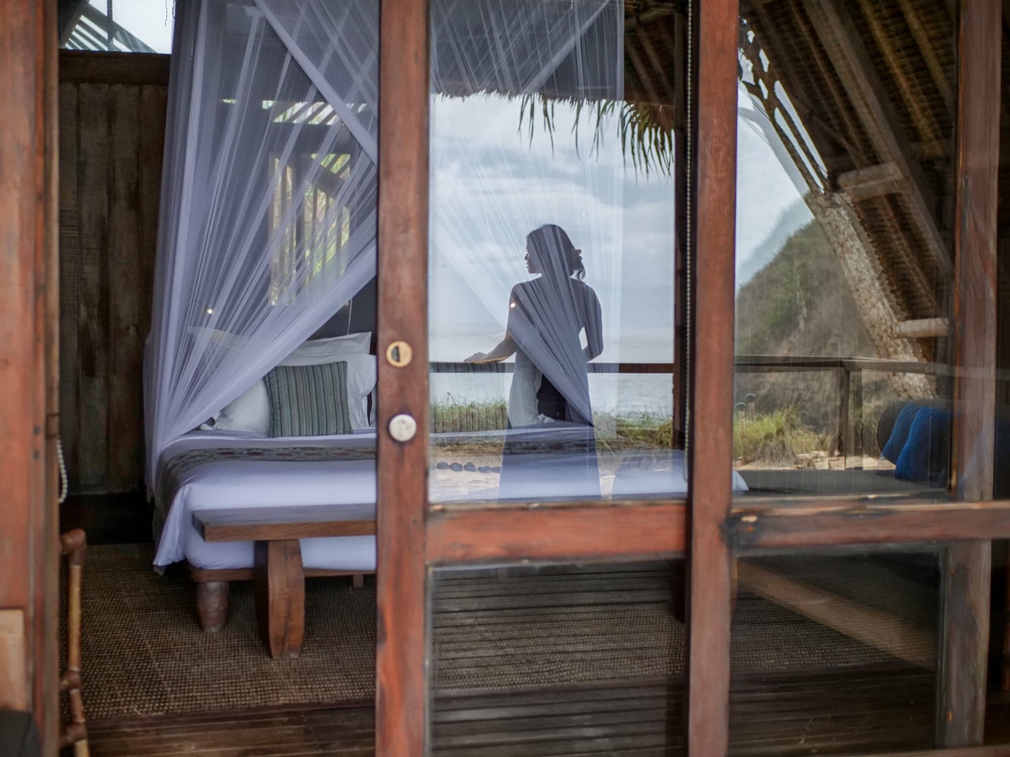 Lodge bedroom interior with carved wooden bed and high thatched bamboo ceiling