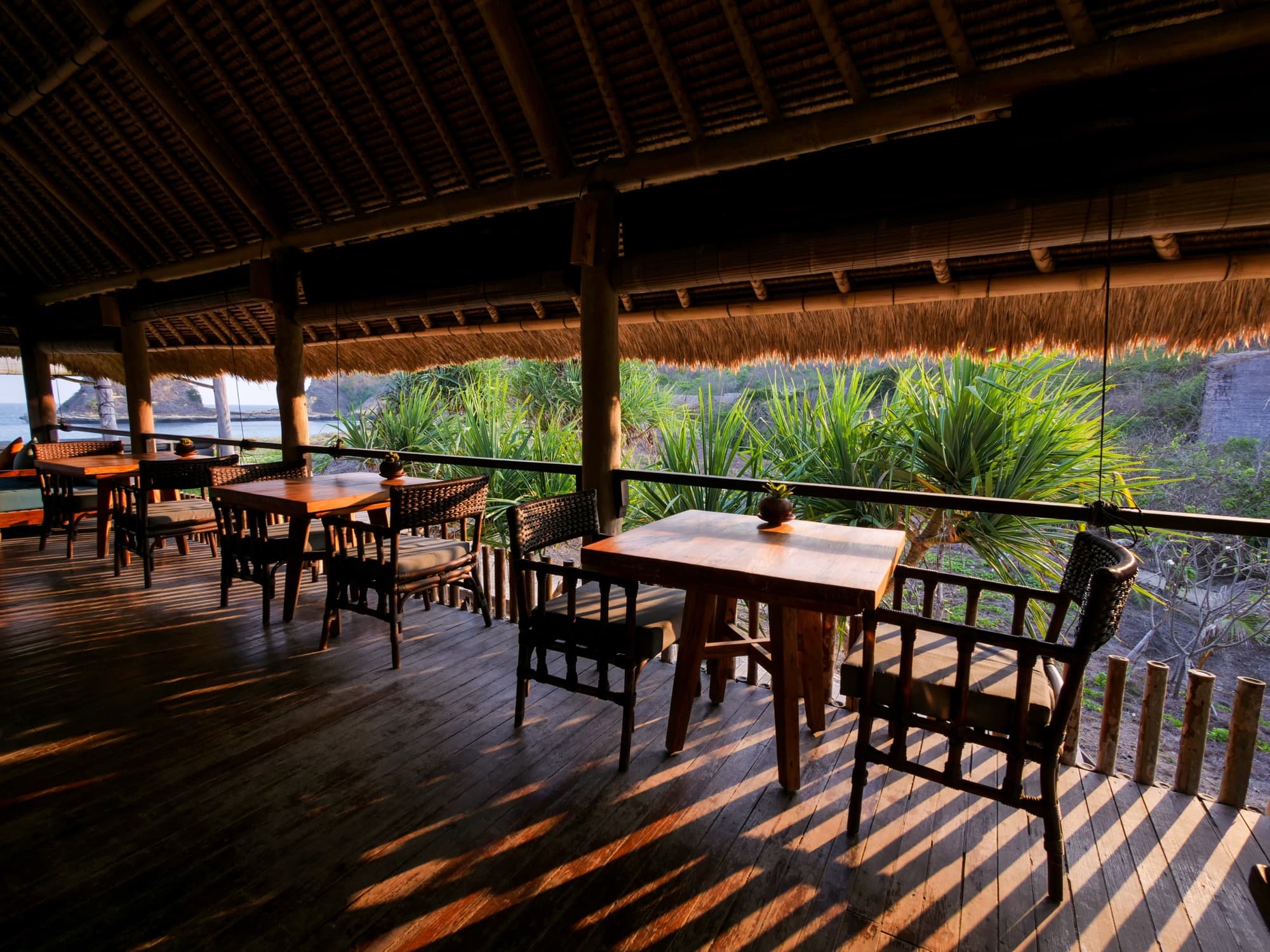 Open-air Dermaga restaurant with wooden tables, rattan chairs and Indian Ocean views