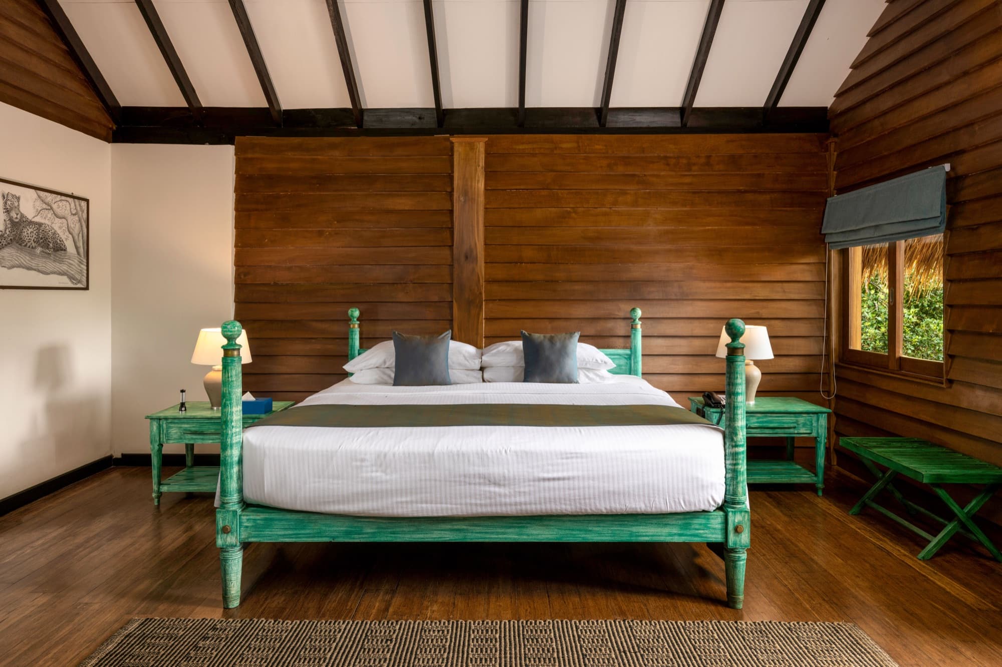 Wooden cabin bedroom with green four-poster bed under a pitched ceiling