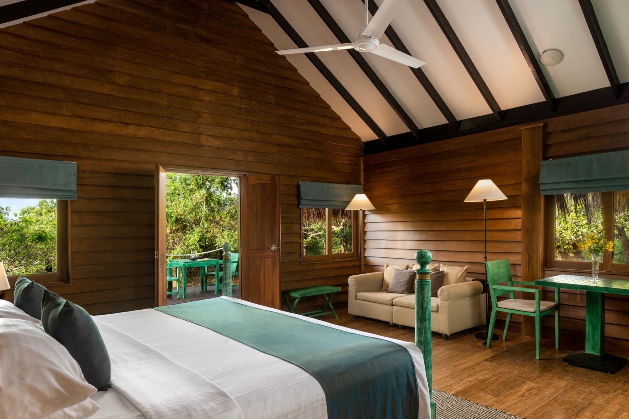 Open cabin interior with high pitched ceiling, ceiling fan and view onto the terrace