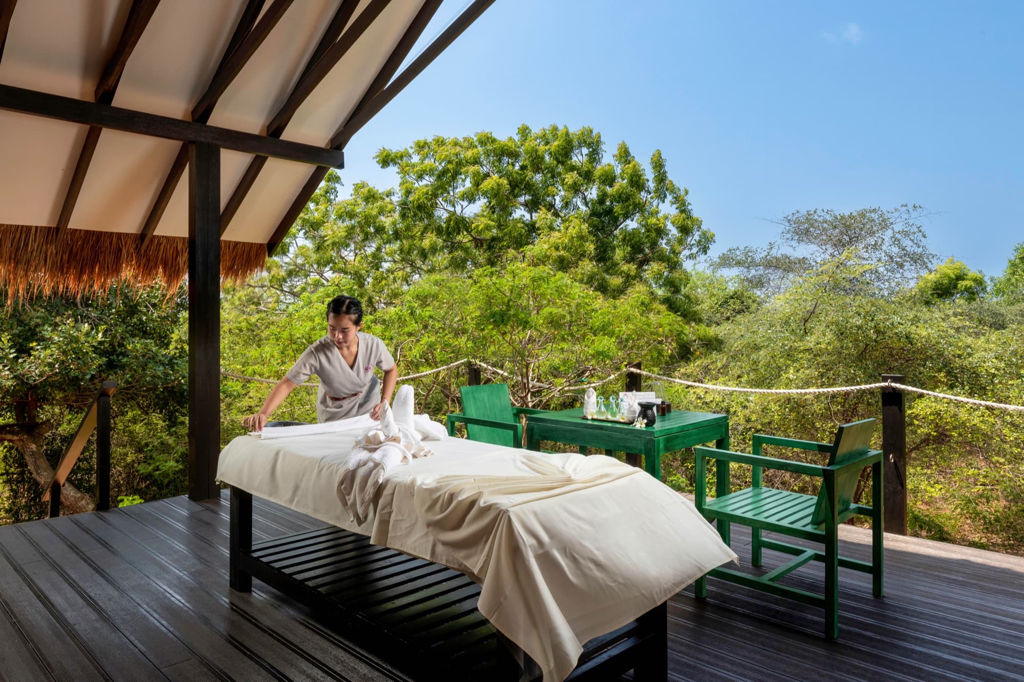 Outdoor massage on a wooden deck open to the surrounding jungle