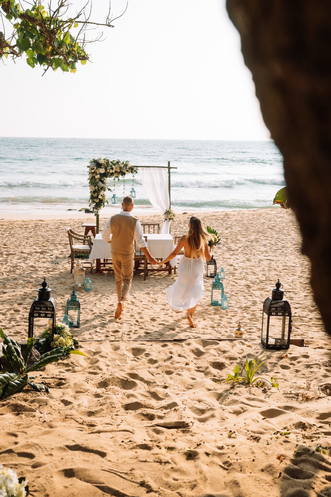 A couple walking to a private table set on the beach by the ocean
