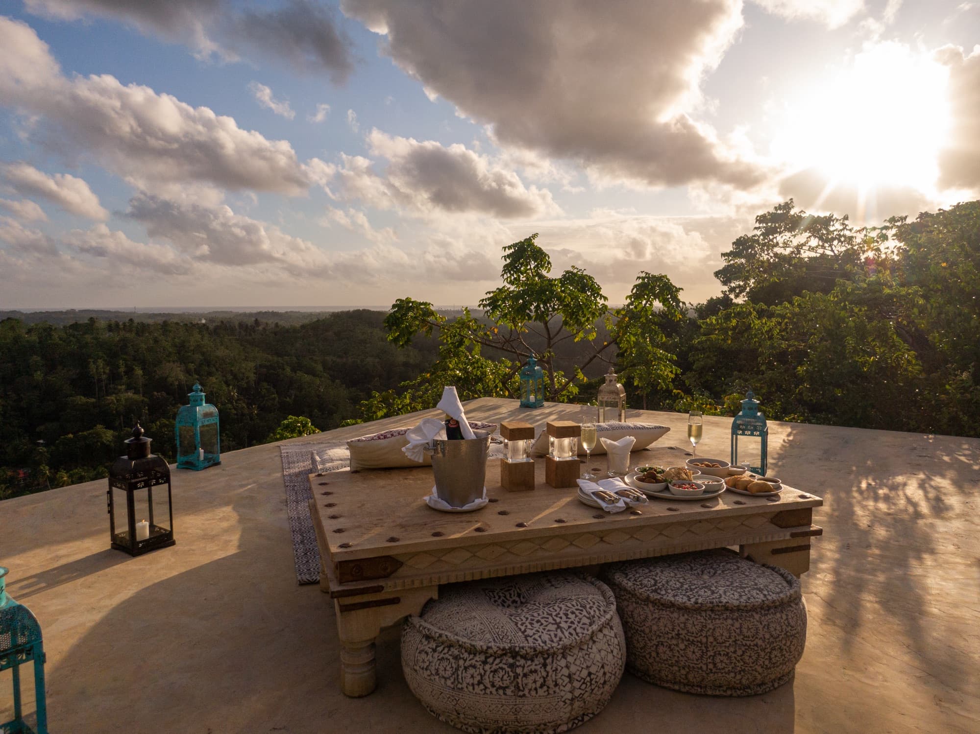 A rooftop table set for dinner at sunset above the treetops