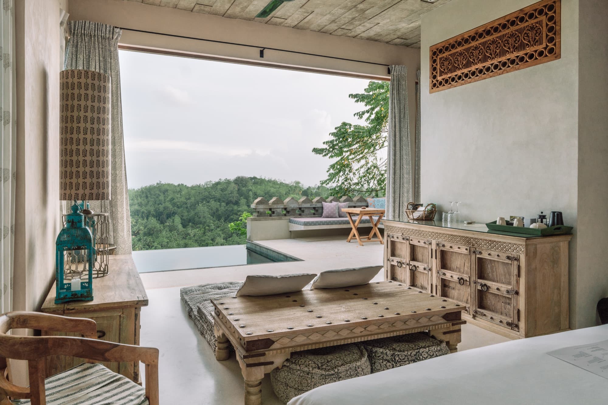 View from a villa bed through full-width glass to the hills and paddies