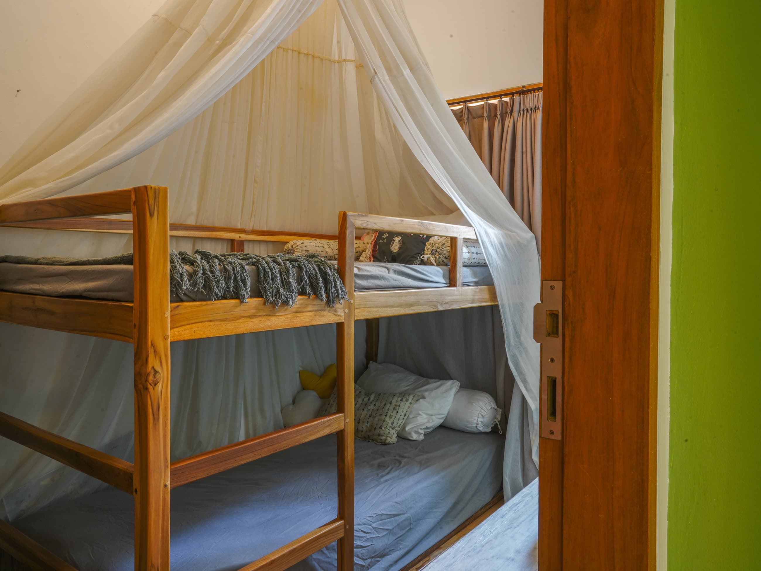 Chambre à lits superposés de la villa avec cadres en bois et moustiquaire drapée