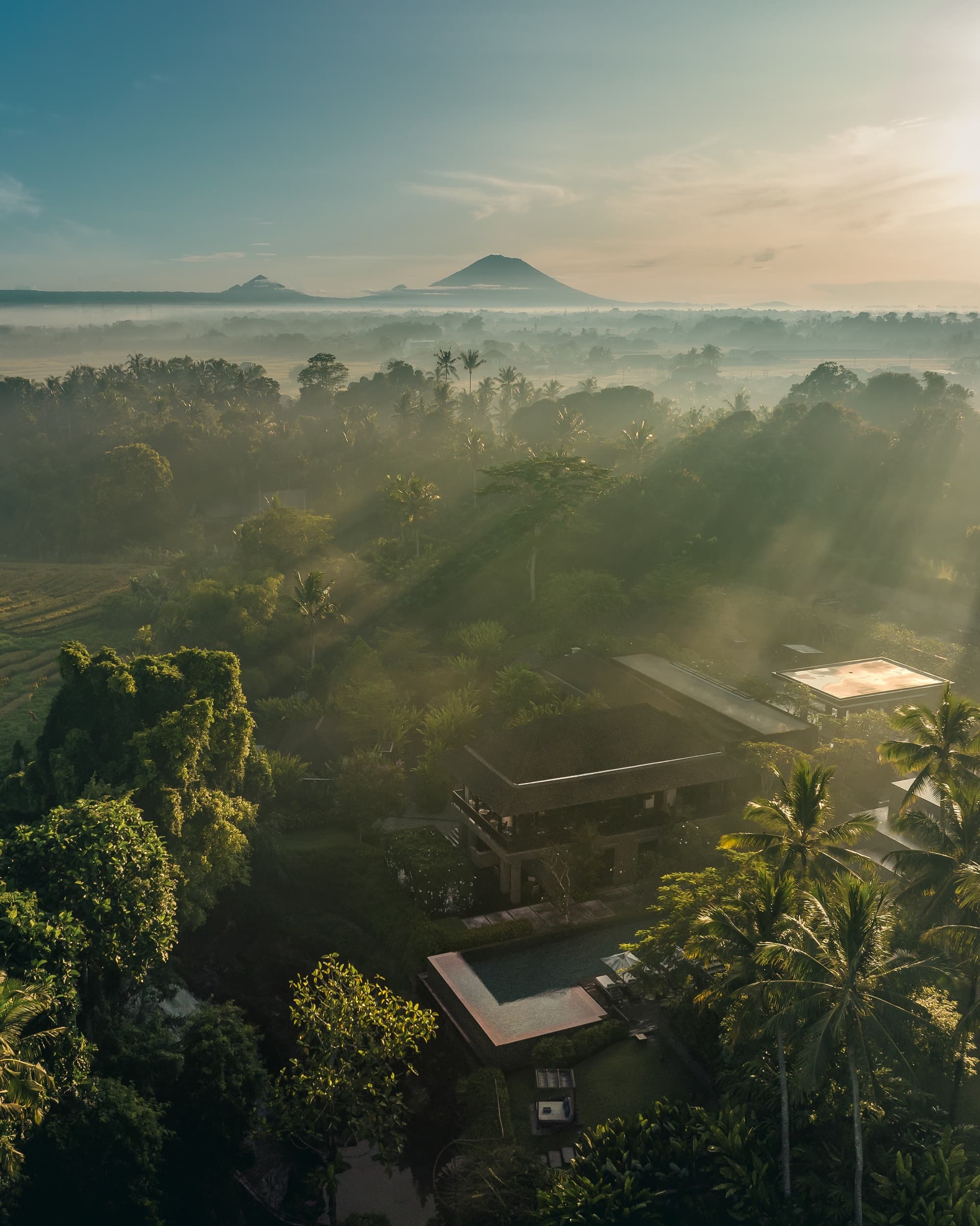 Misty sunrise over the resort with Bali's volcanoes on the horizon