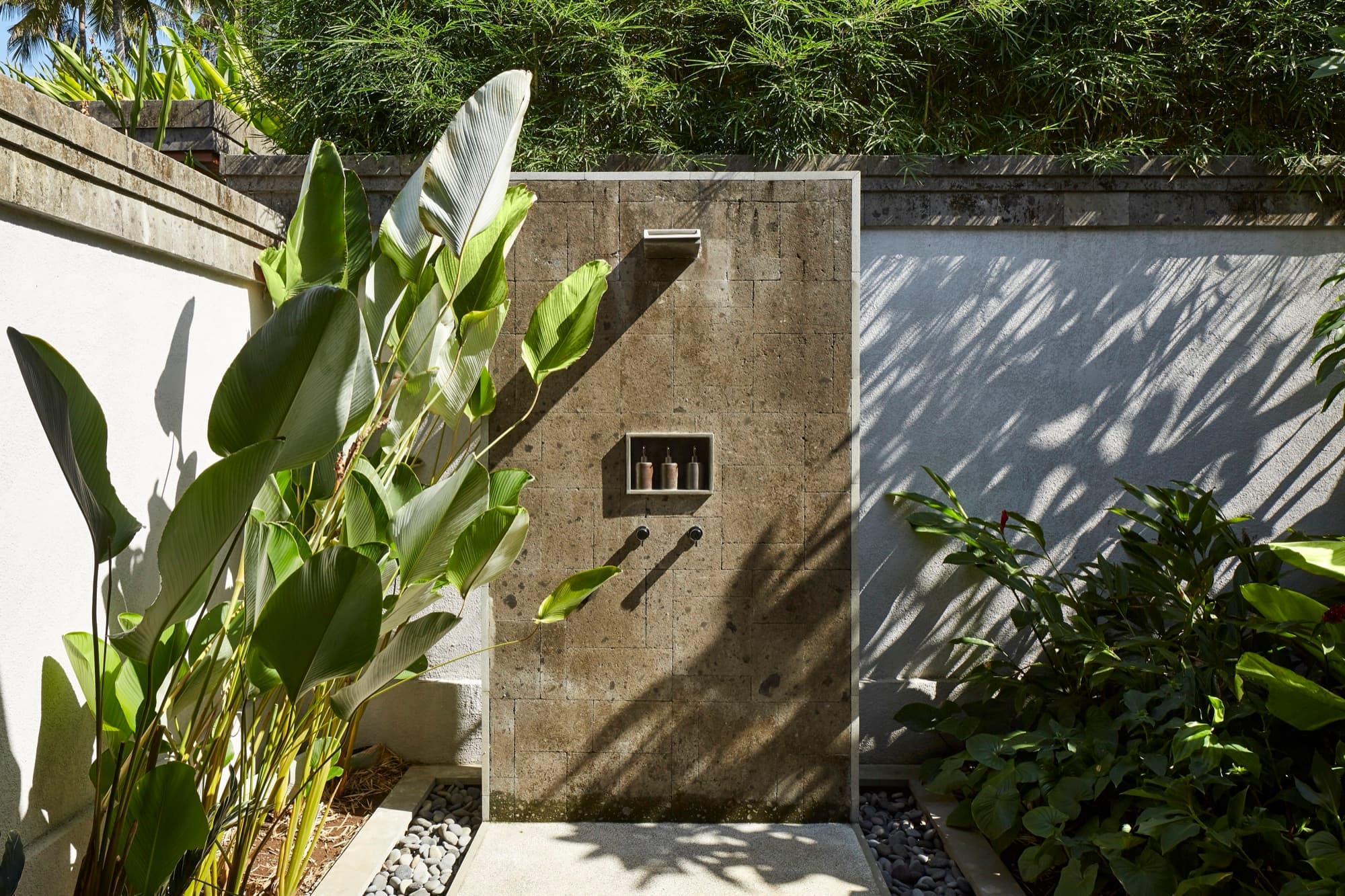 Open-air stone shower framed by tropical plants at a Jungle Pool Pavilion