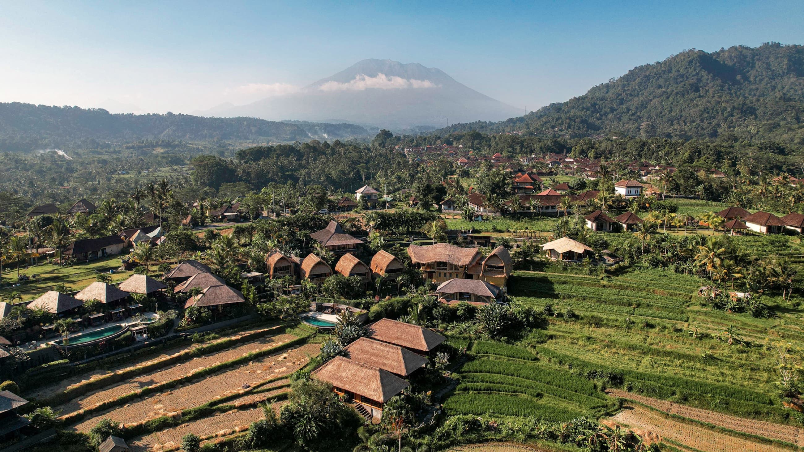 Aerial view of Samanvaya resort — thatched Joglo villas among rice terraces with Mount Agung, Sidemen valley, east Bali