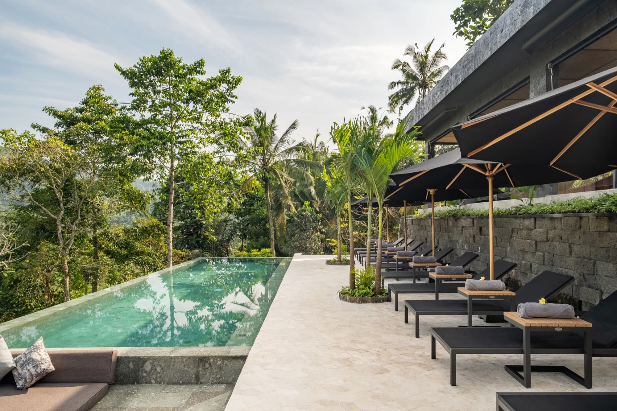 Wellness pool area with sun loungers and tropical vegetation at Samanvaya