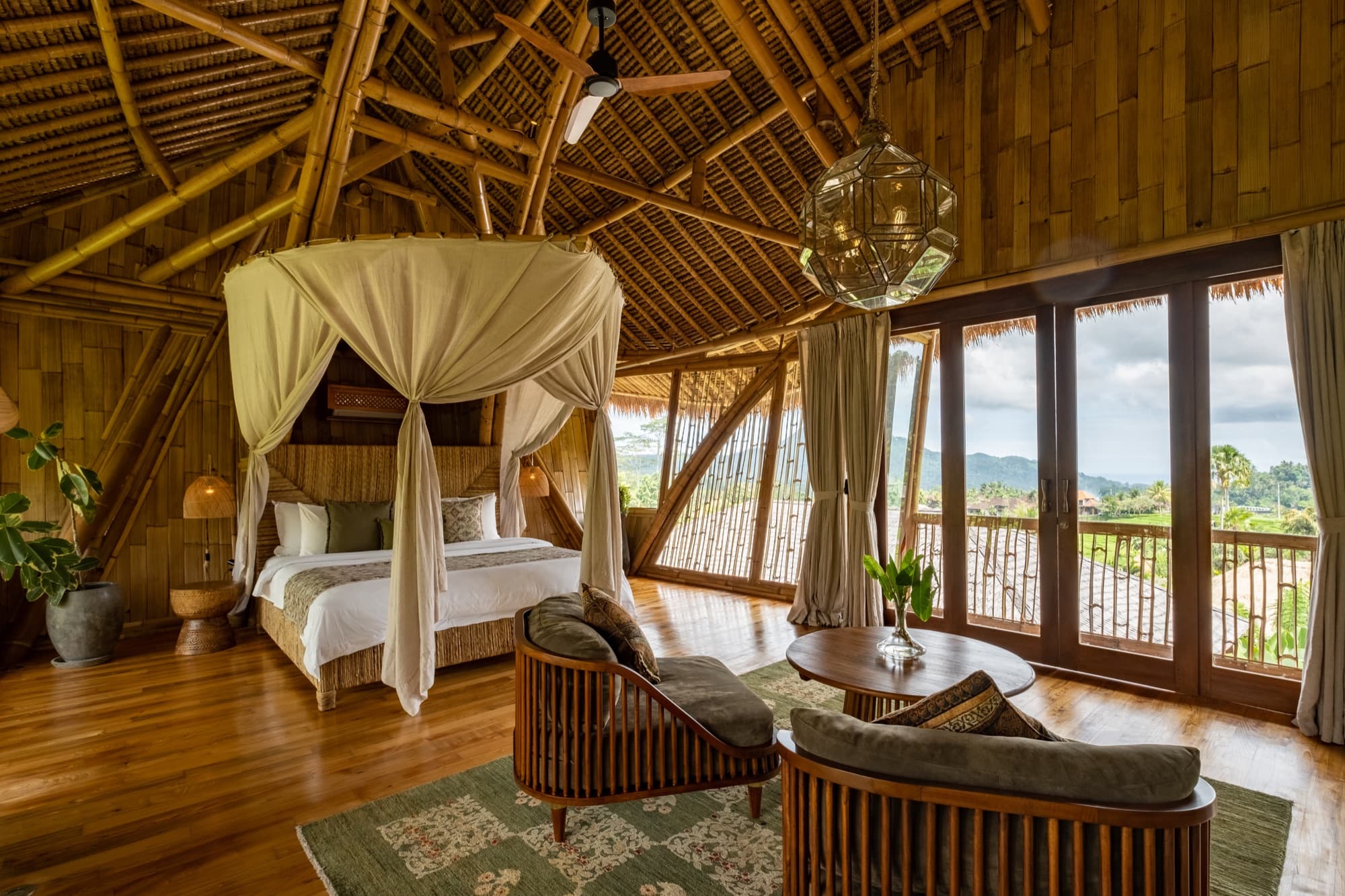 Batari villa bedroom — full bamboo structure with canopy bed and rice field views