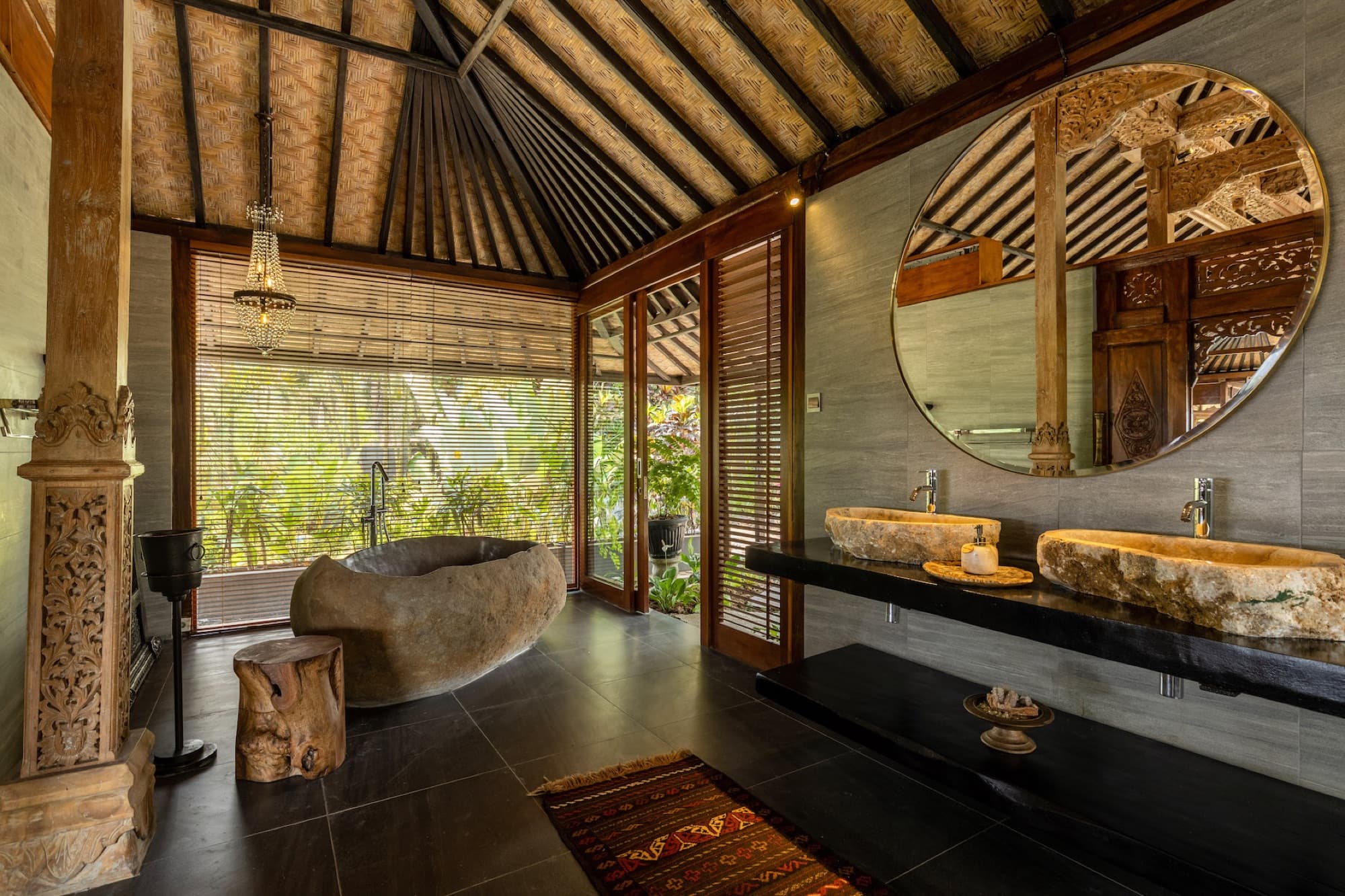 Joglo villa bathroom with carved wooden pillars and traditional Balinese stone finishes