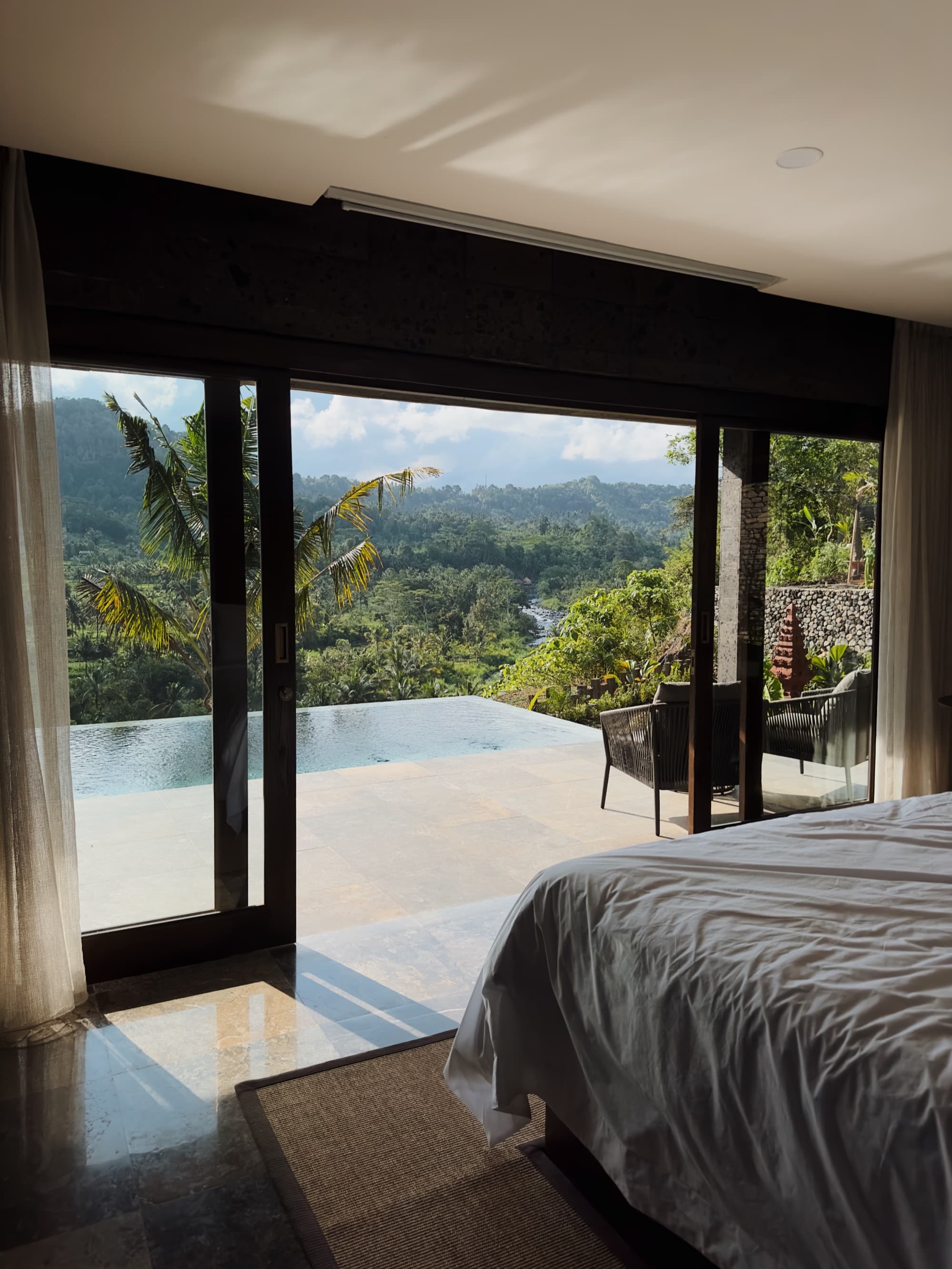 Mulia Wellness Villa bedroom opening onto private infinity pool and river valley
