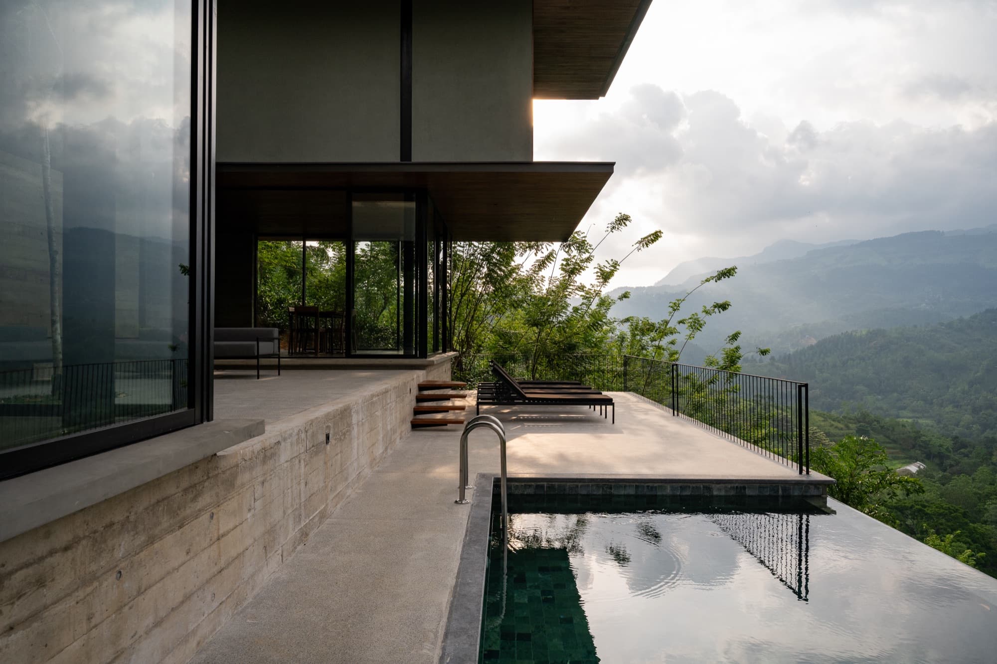 Private plunge pool and loungers on a villa terrace above a misty mountain valley