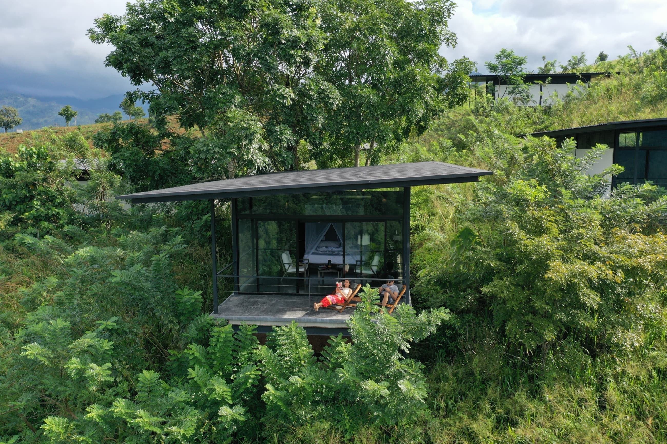 Glass-walled Mountain View Chalet raised on a deck amid hillside greenery — Santani, near Kandy, Sri Lanka