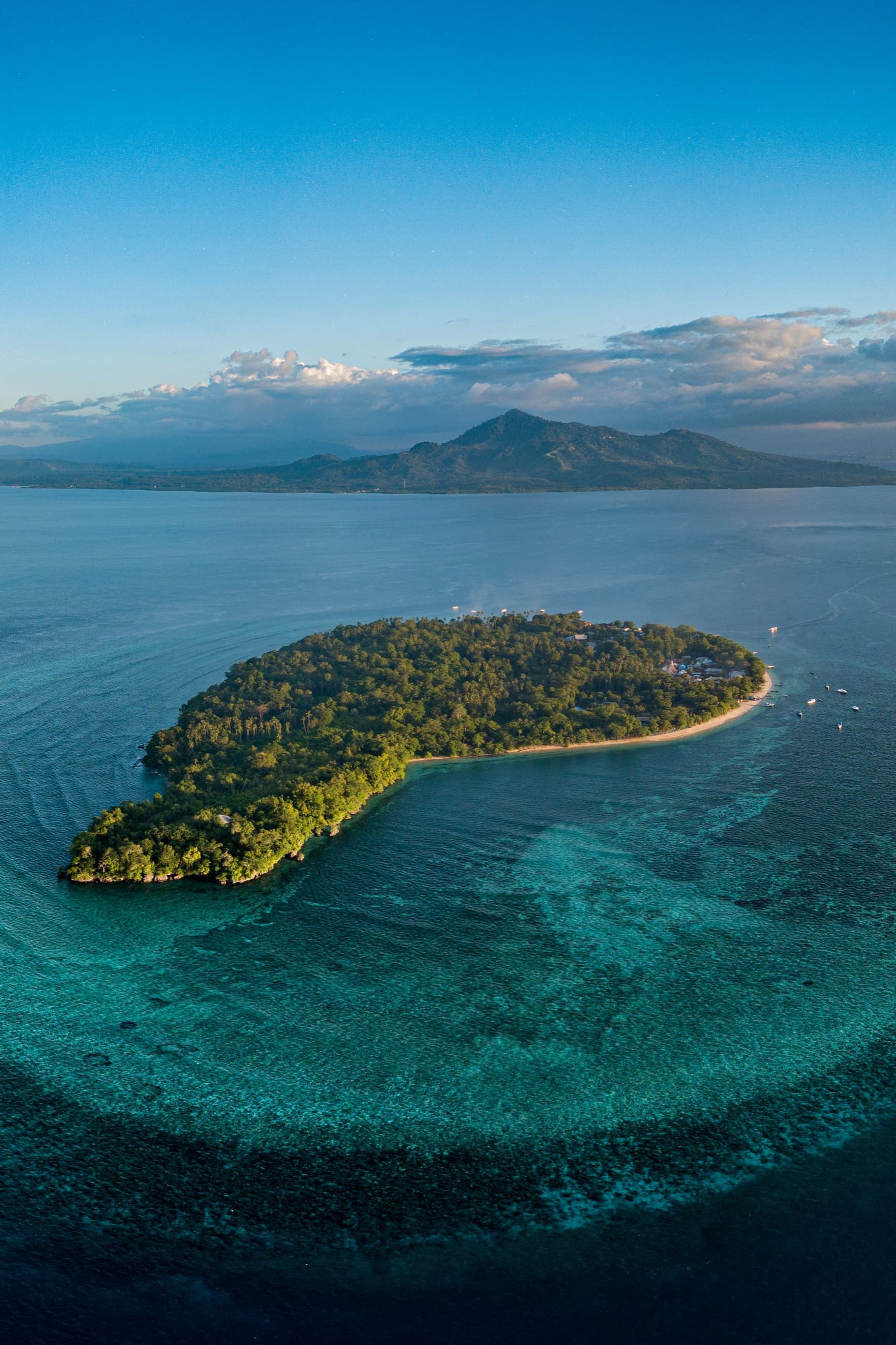 Aerial view of Siladen island and its fringing reef, with Manado Tua beyond, Bunaken Marine Park