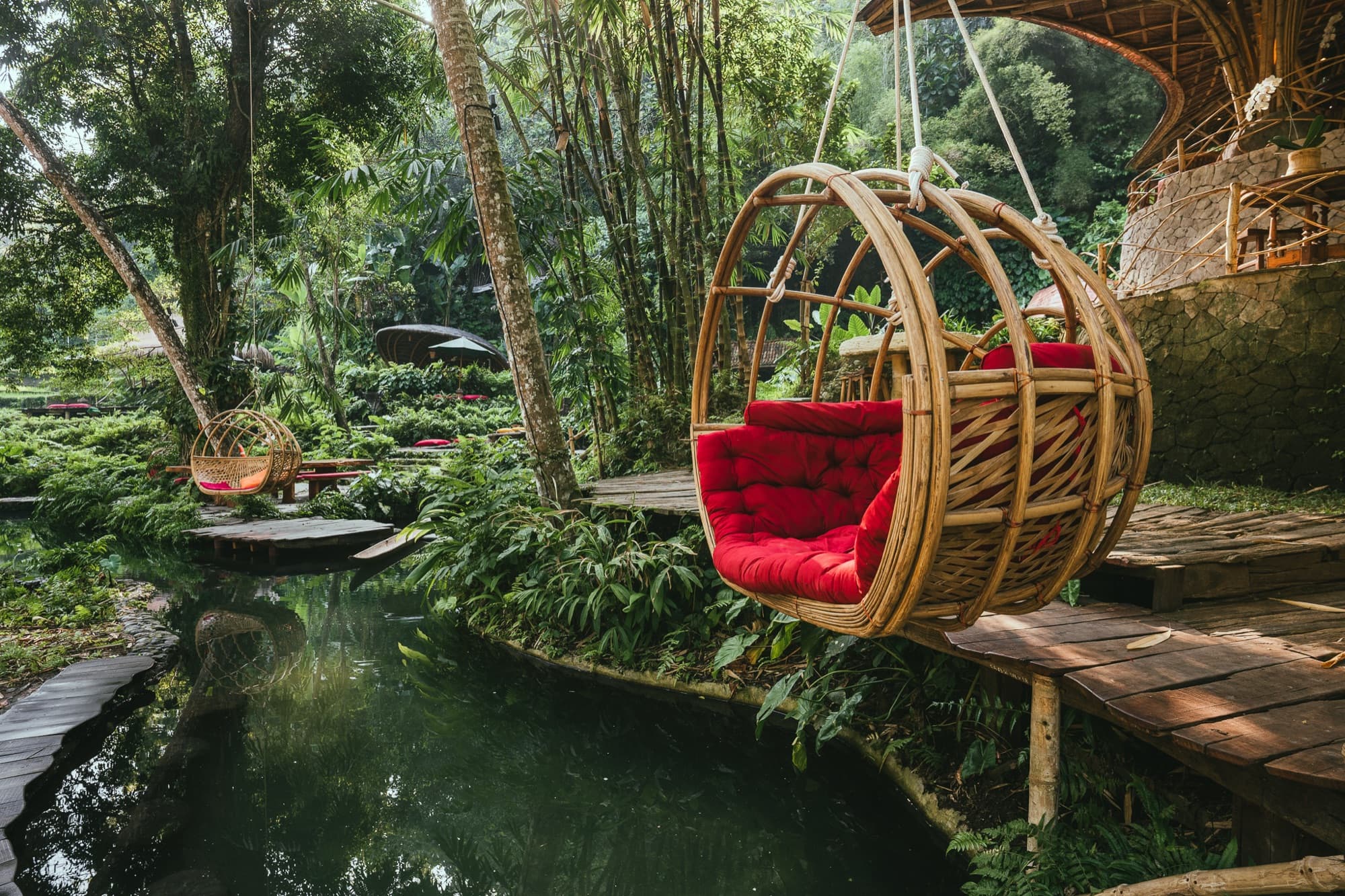 Hanging rattan chairs above a spring-fed pond in the gardens