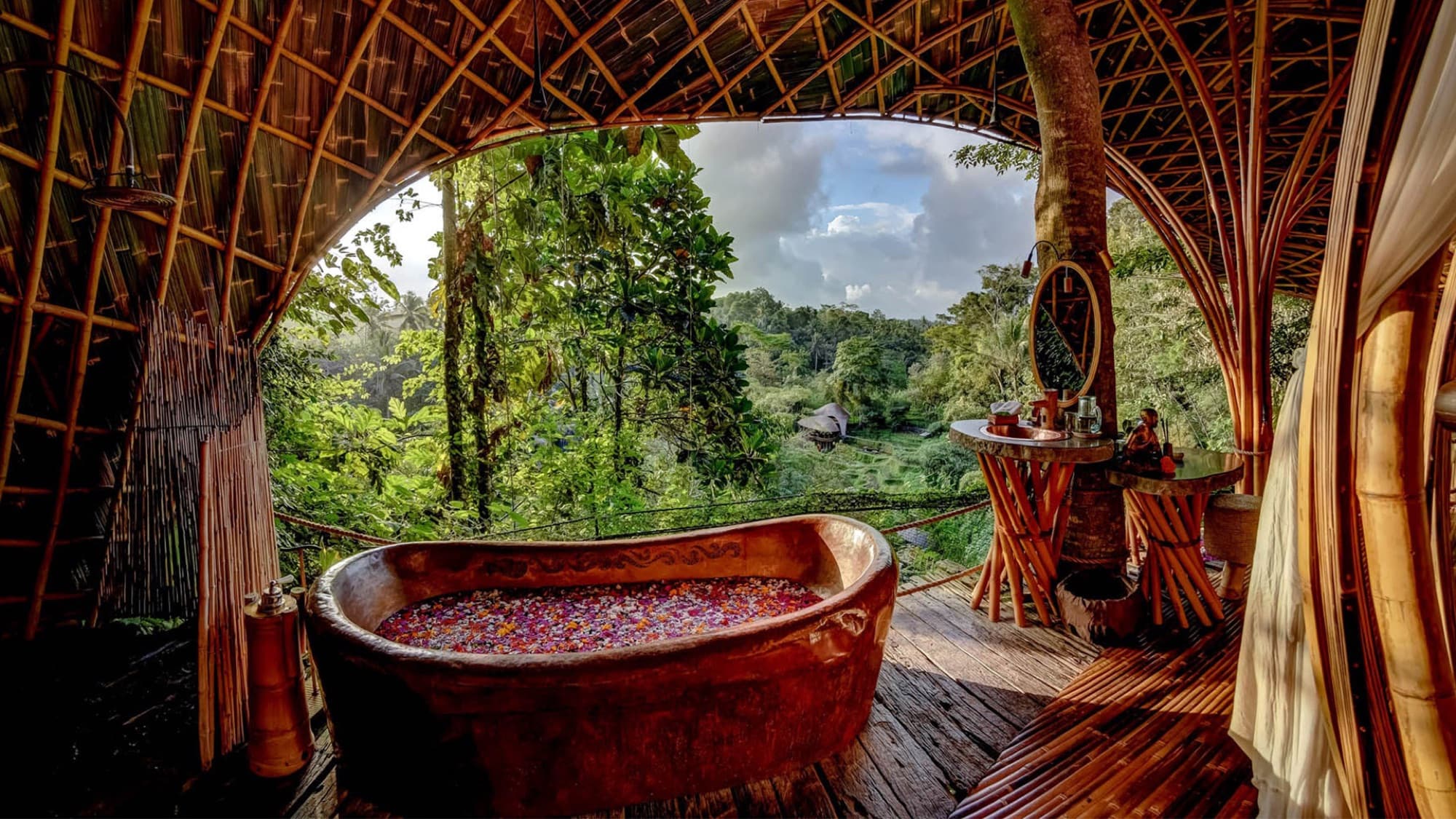 Copper bathtub open to the jungle canopy inside a bamboo house