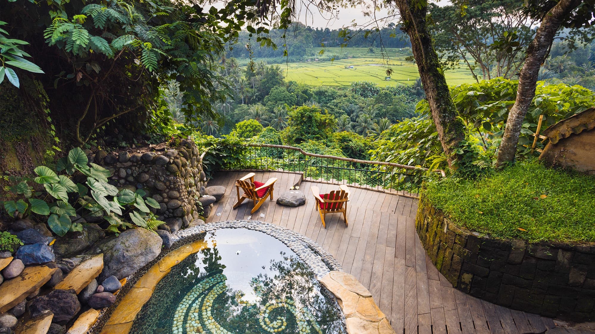 Stone spiral plunge pool and timber deck overlooking rice terraces