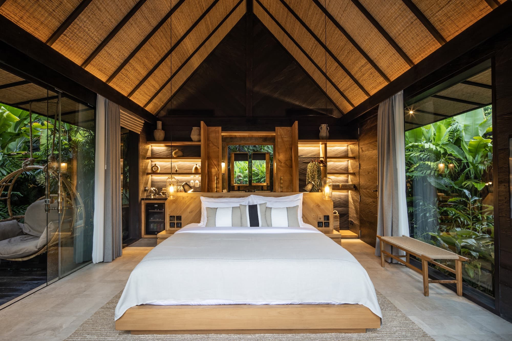 Villa bedroom under a cathedral timber roof, open on both sides to the garden