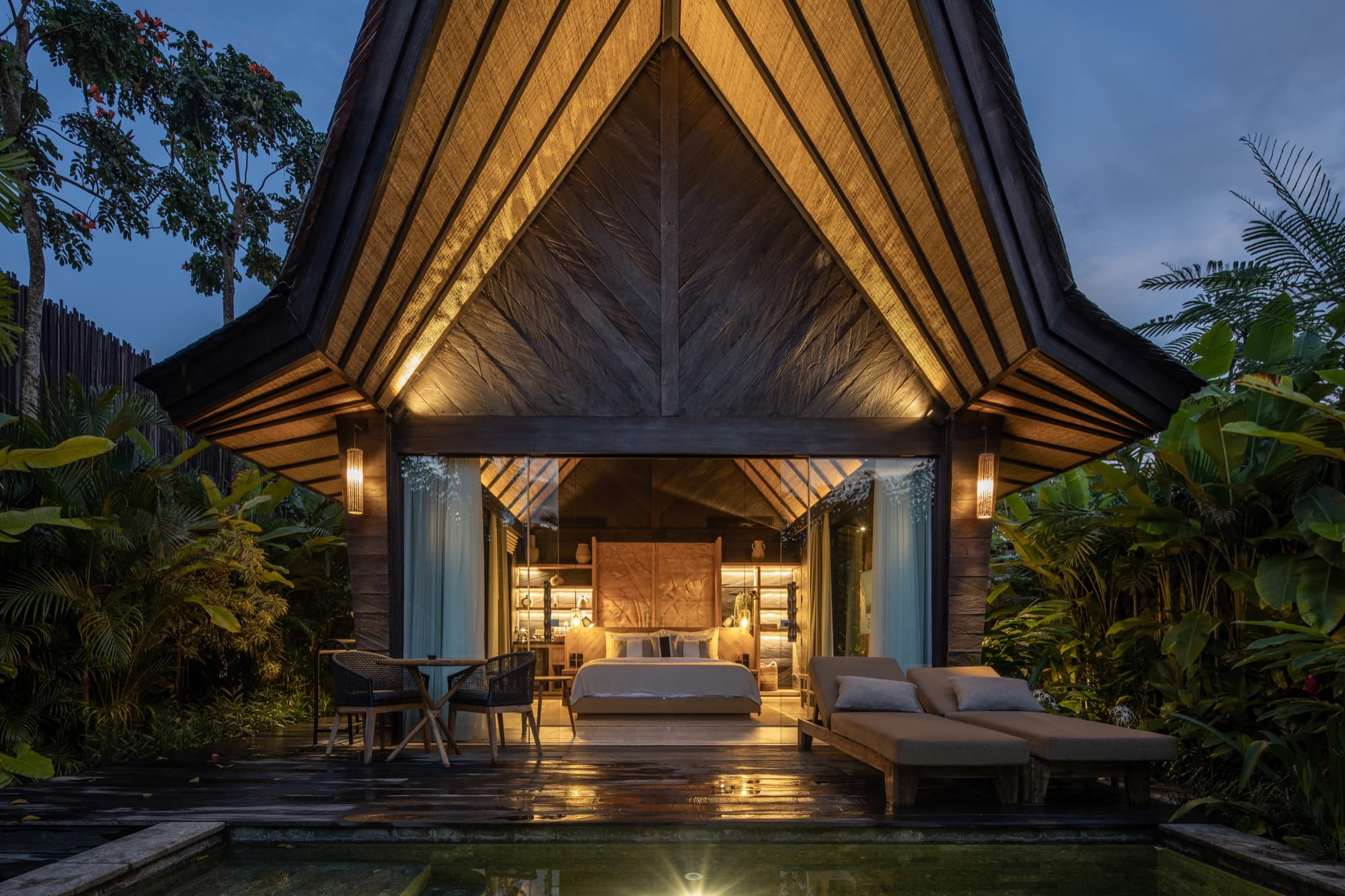 Villa open to its bedroom at dusk, with a private plunge pool on the deck