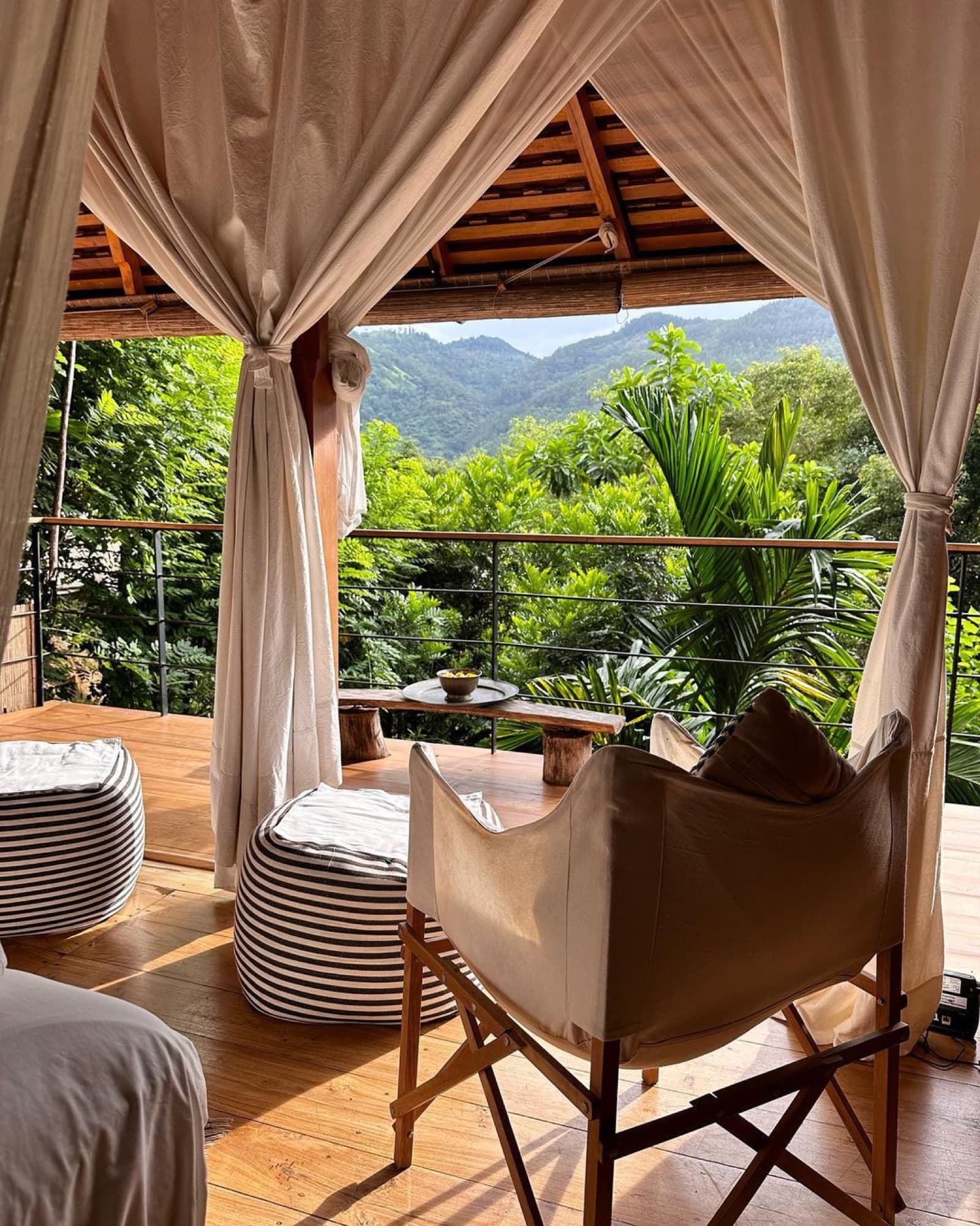 Forest Pavilion deck with canvas chairs and curtains framing the surrounding mountains