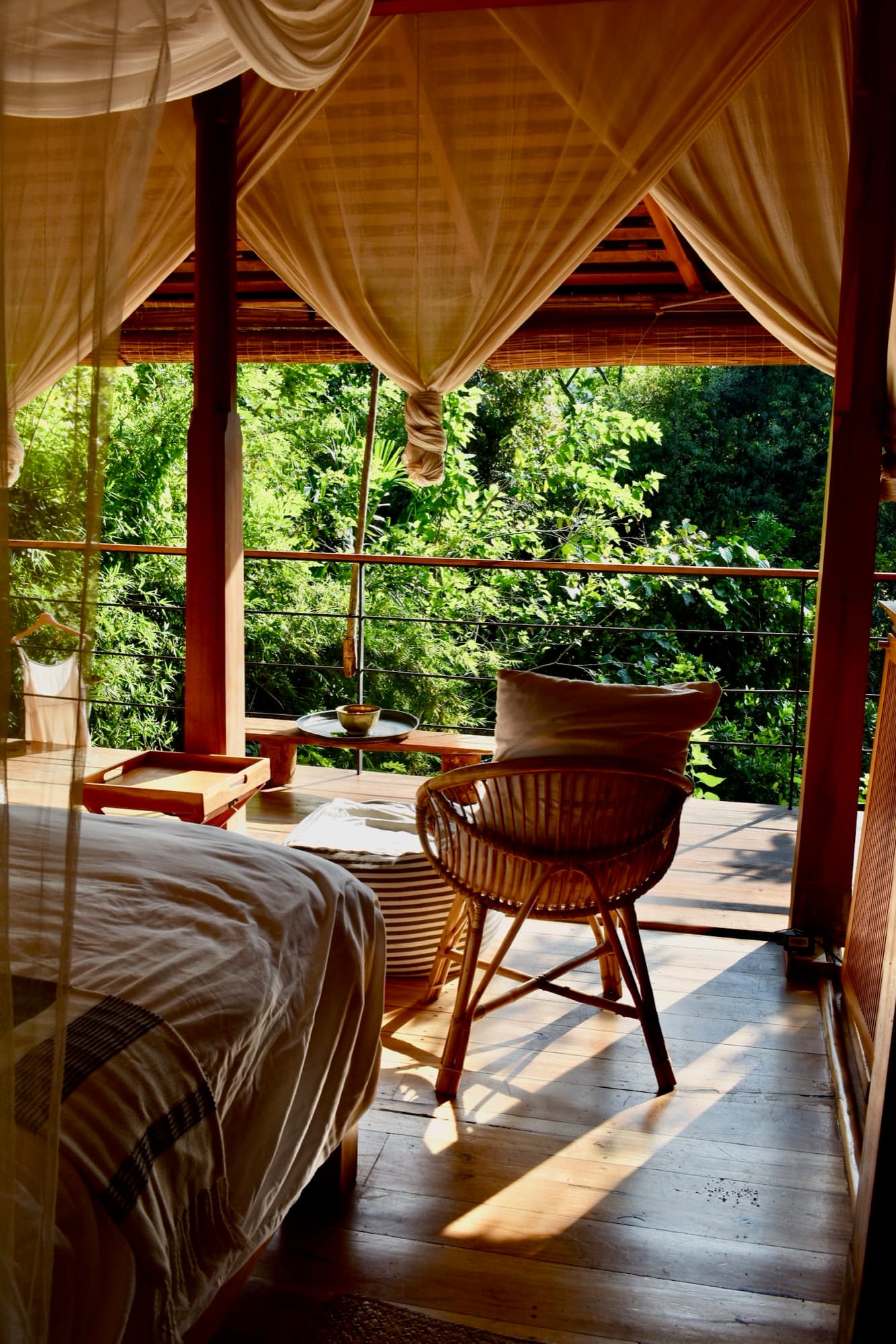 Forest Pavilion bed under a mosquito net beside a balcony over the treetops