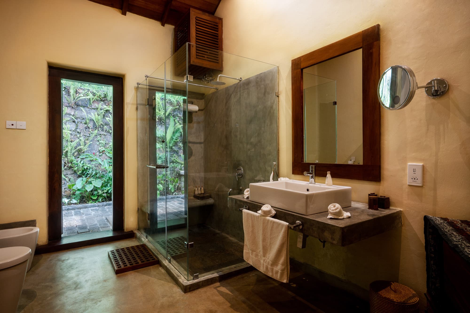 Villa Suite bathroom with a glass shower opening onto a walled garden