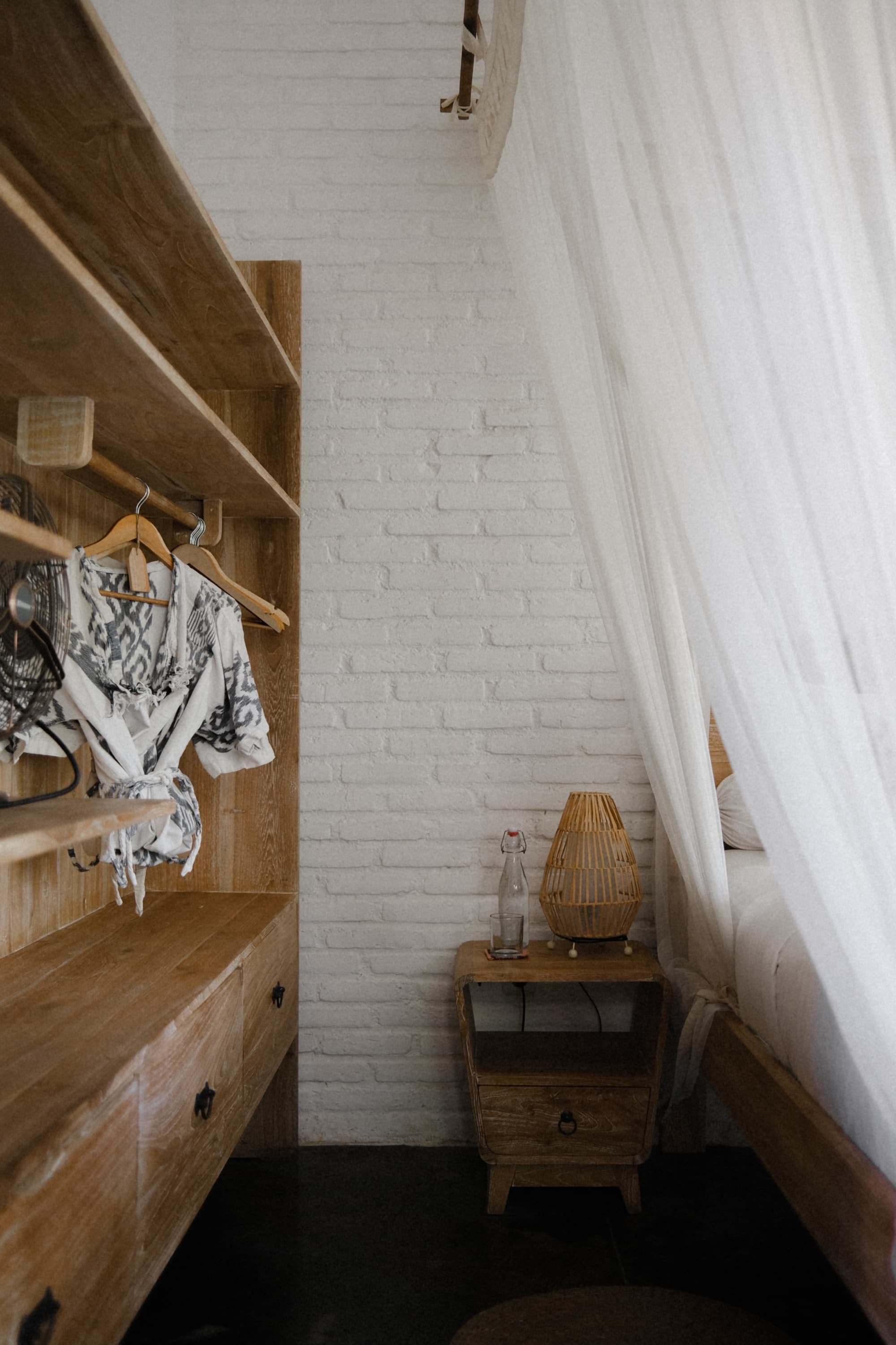 Canopy bed in a curved-wall room with dark timber floor and garden windows