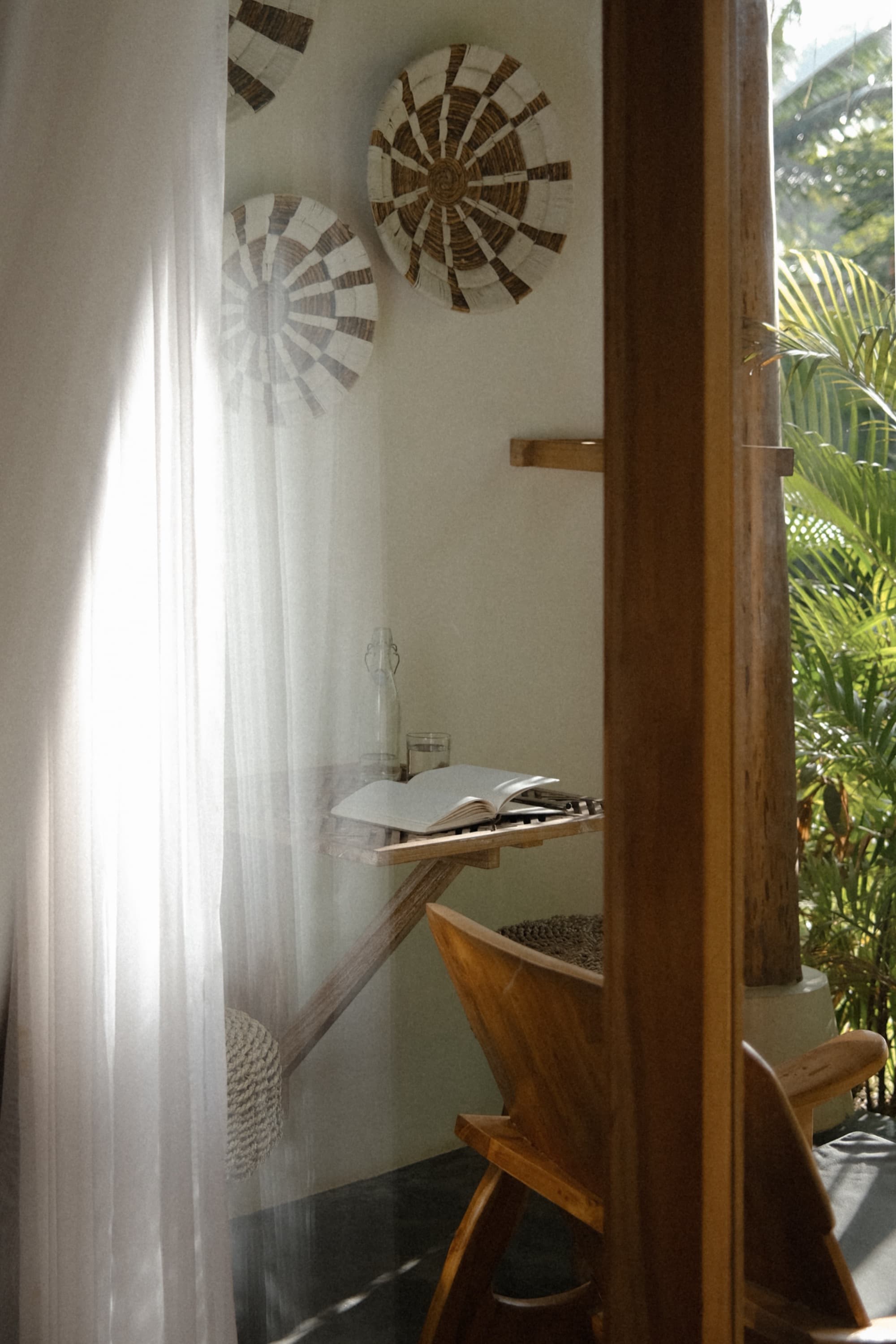 Reading nook with a woven wall hanging, timber desk and sheer curtain