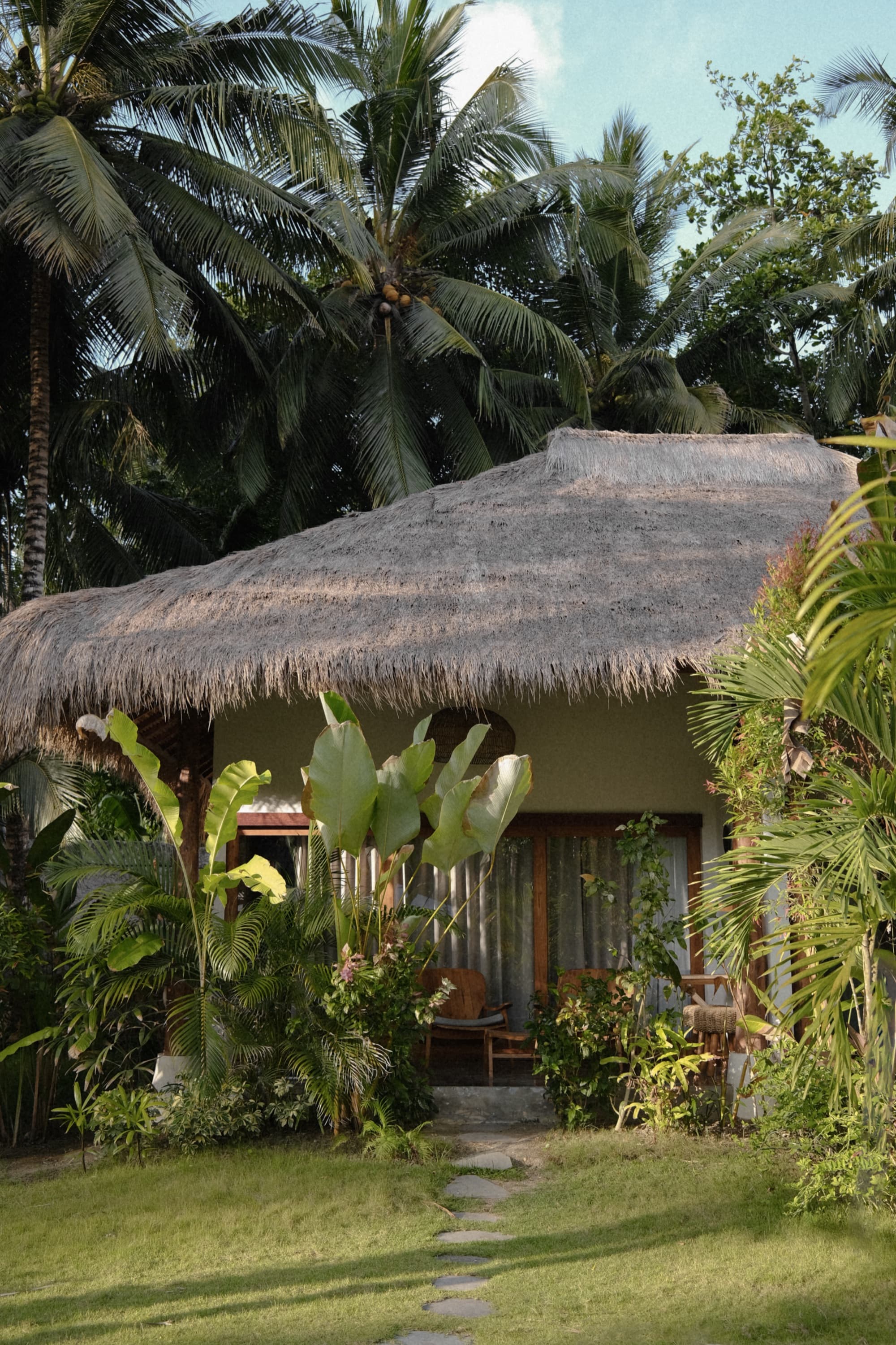 Thatched bungalow set among coconut palms and tropical planting
