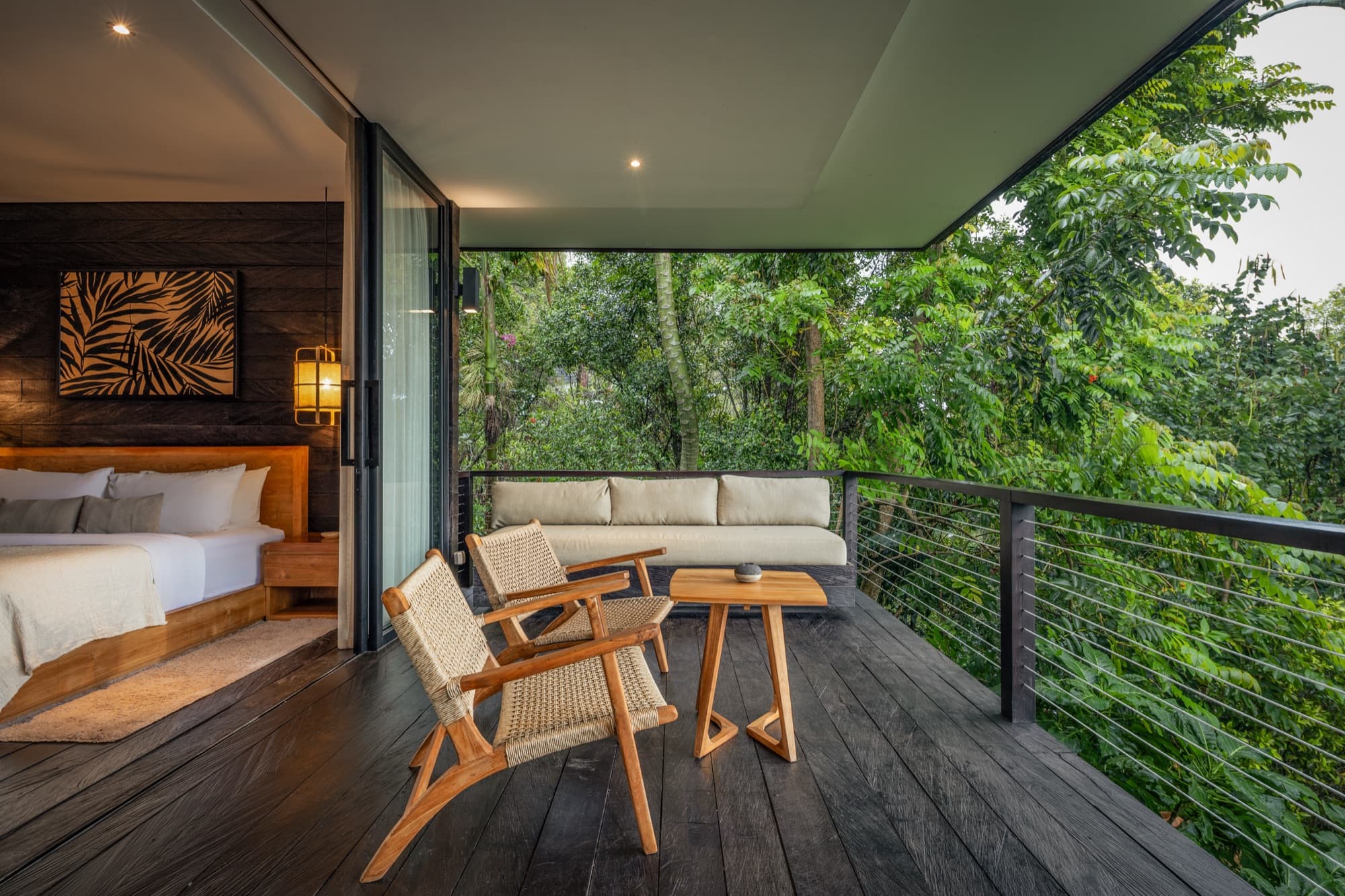 Private cabin deck with woven chairs and a sofa overlooking the rainforest canopy