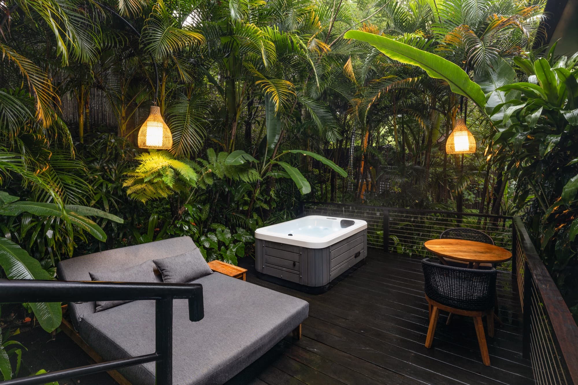 Private cabin deck with an outdoor hot tub and a daybed set among the jungle