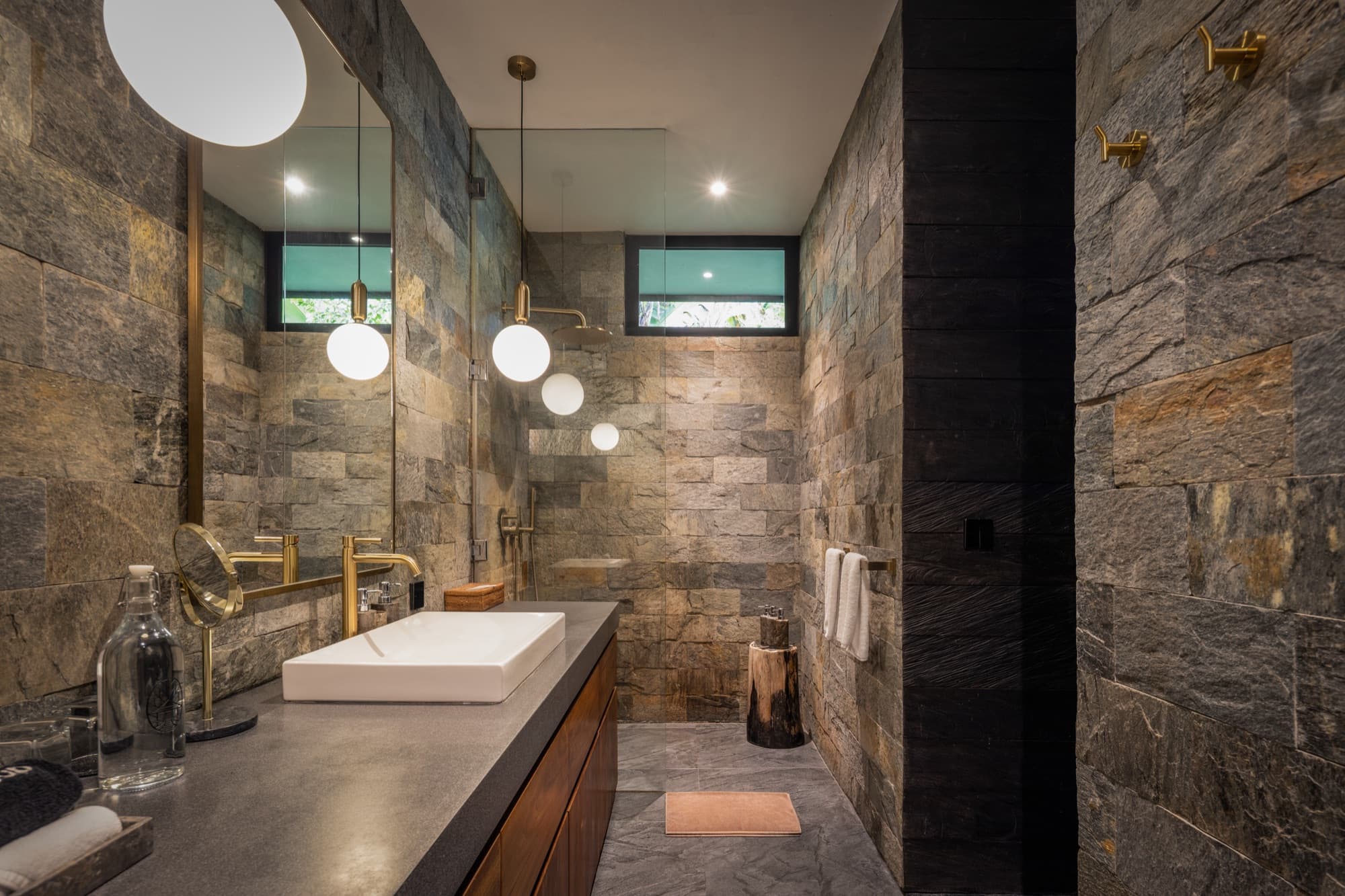Cabin bathroom clad in local stone with a walk-in shower and brass fittings
