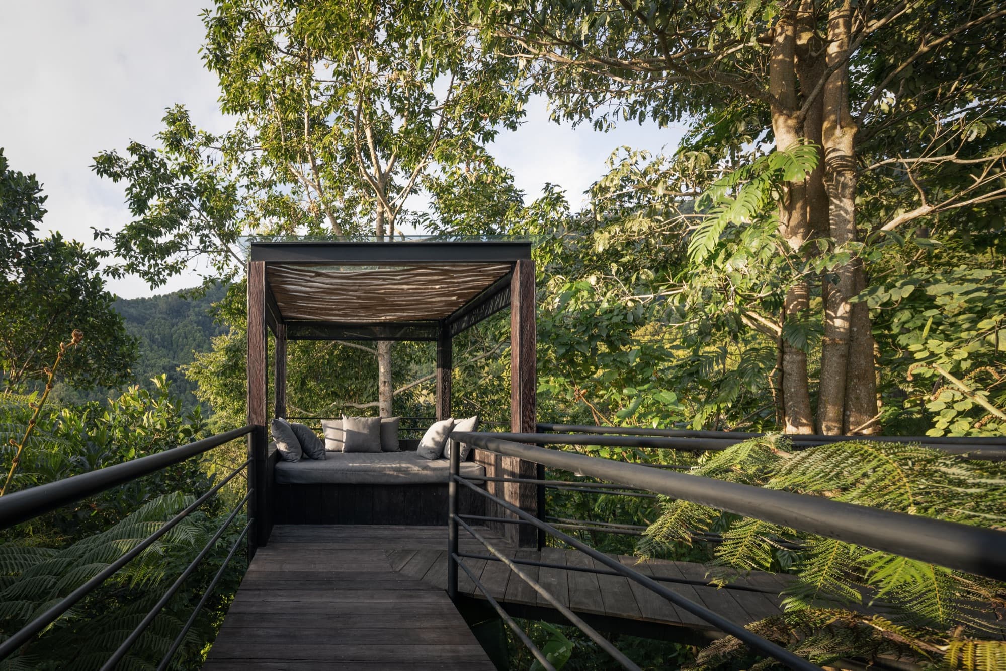 Cushioned daybed cabana on a boardwalk platform projecting into the forest canopy