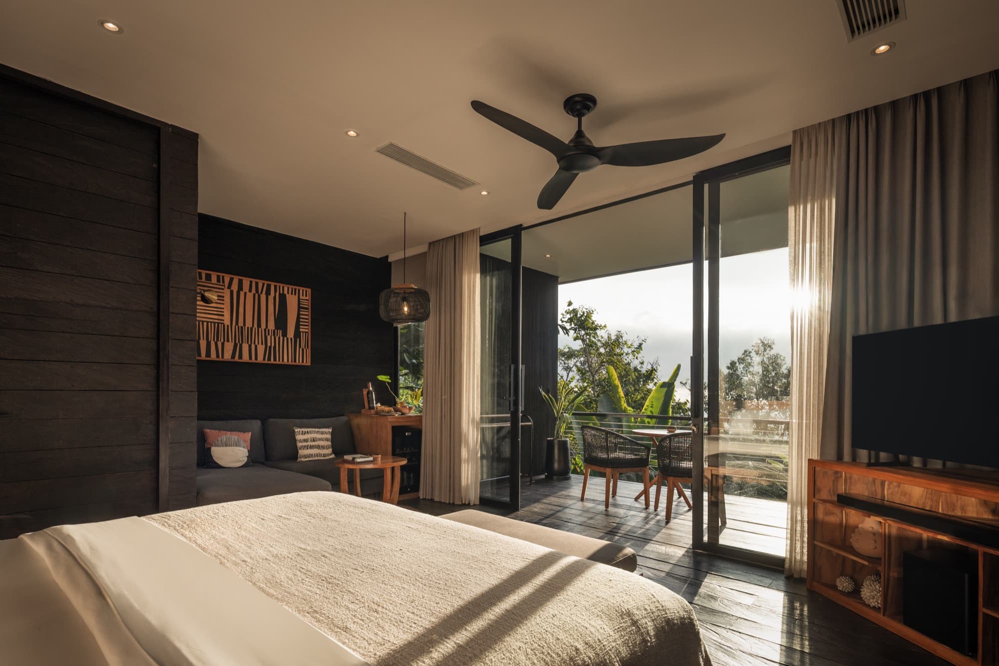 Cabin bedroom with a ceiling fan and open doors framing a hillside view