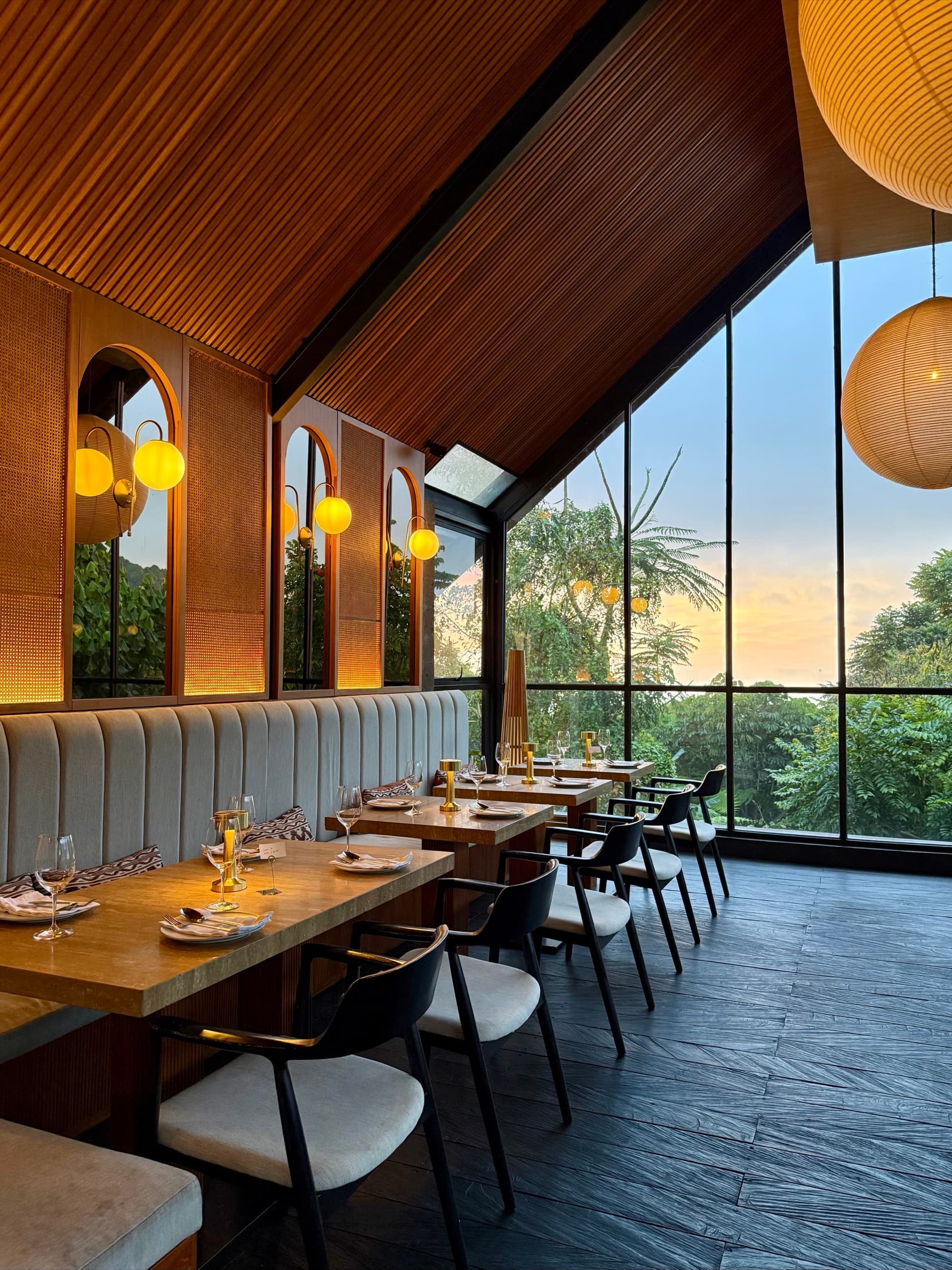 Ulekan restaurant with a vaulted timber ceiling and tall windows opening to the hills at sunset