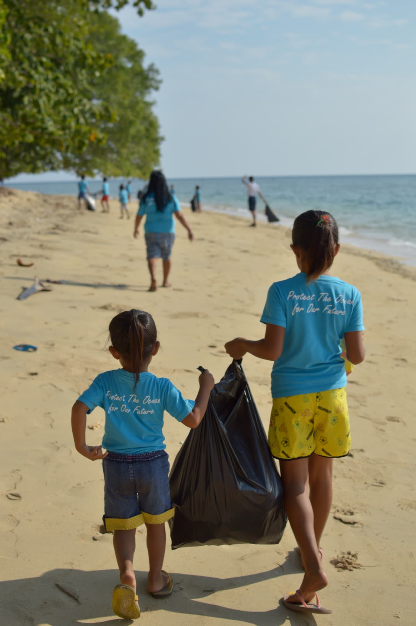 Local children on a beach cleanup in 'Protect the Ocean' shirts at Siladen