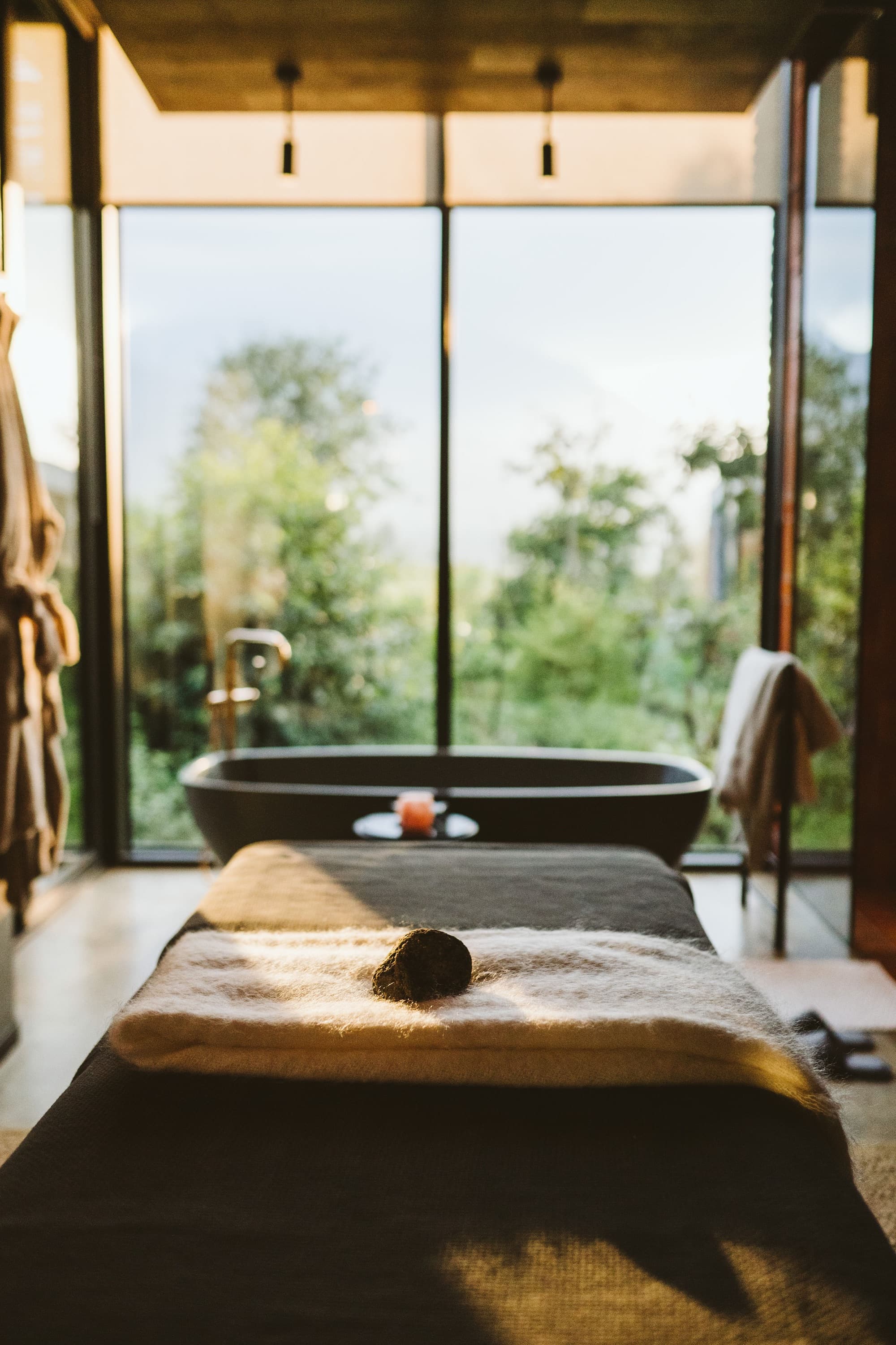 Bathroom with a freestanding bath and a massage table by the window