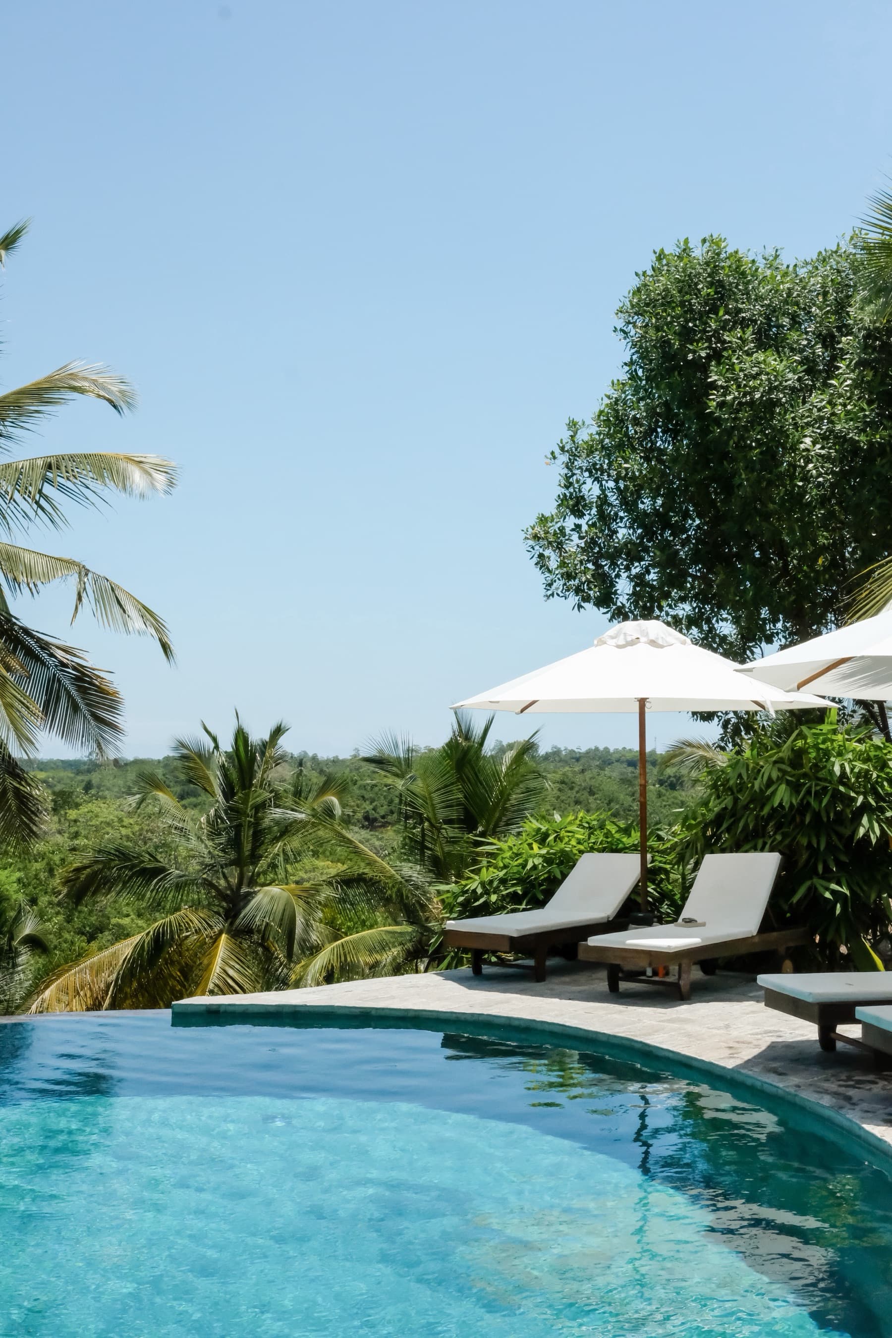 Poolside loungers and umbrella beside the infinity pool under a clear sky