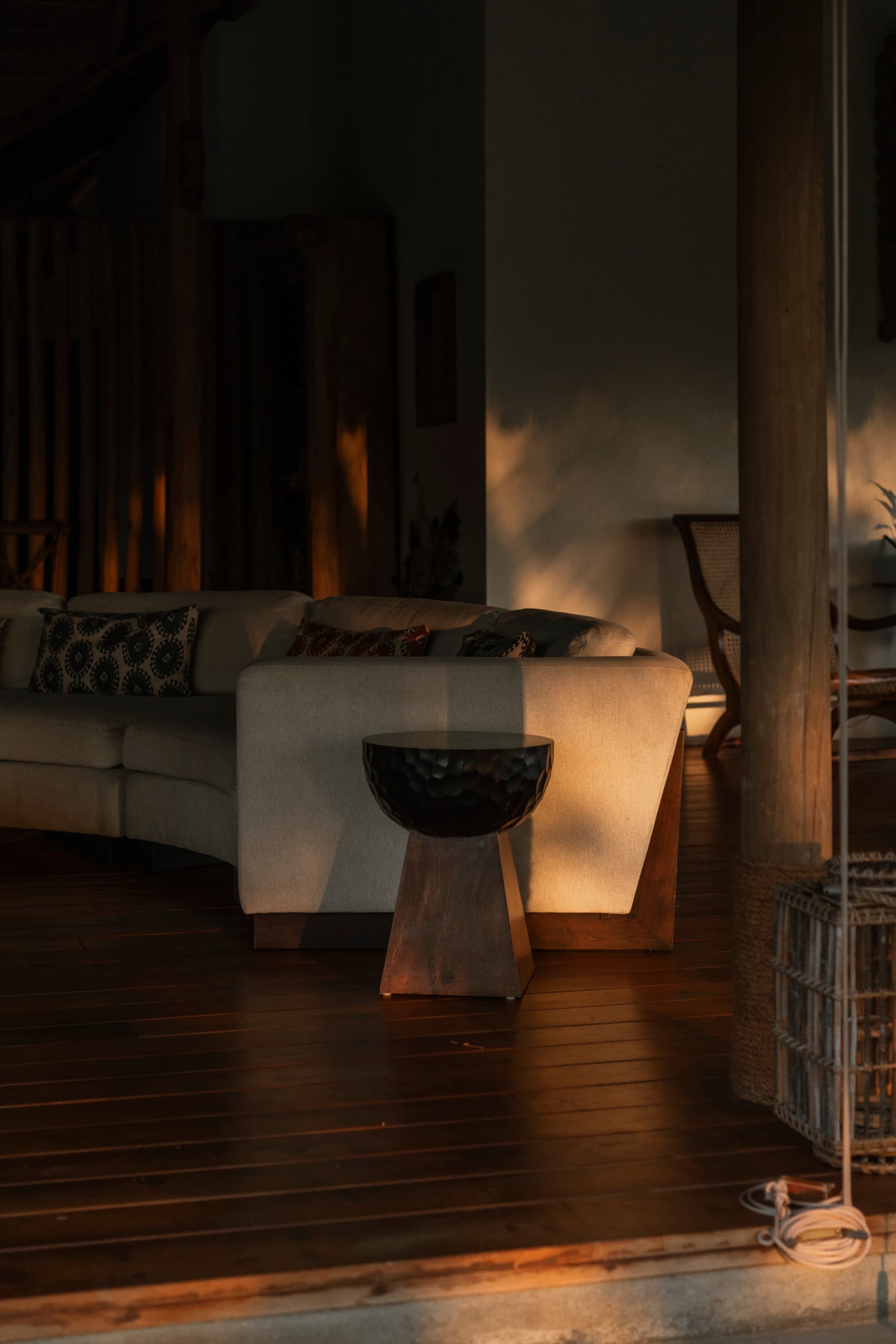 Living area at golden hour with a pale sofa and dark timber floor