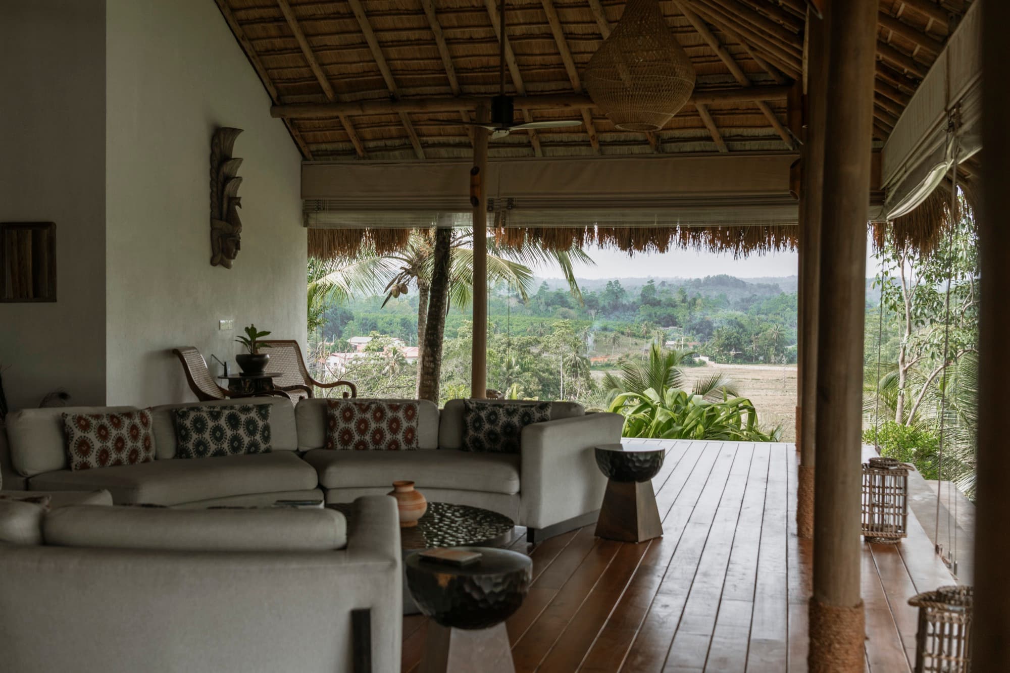 Covered lounge with sofas opening onto a timber deck and valley views