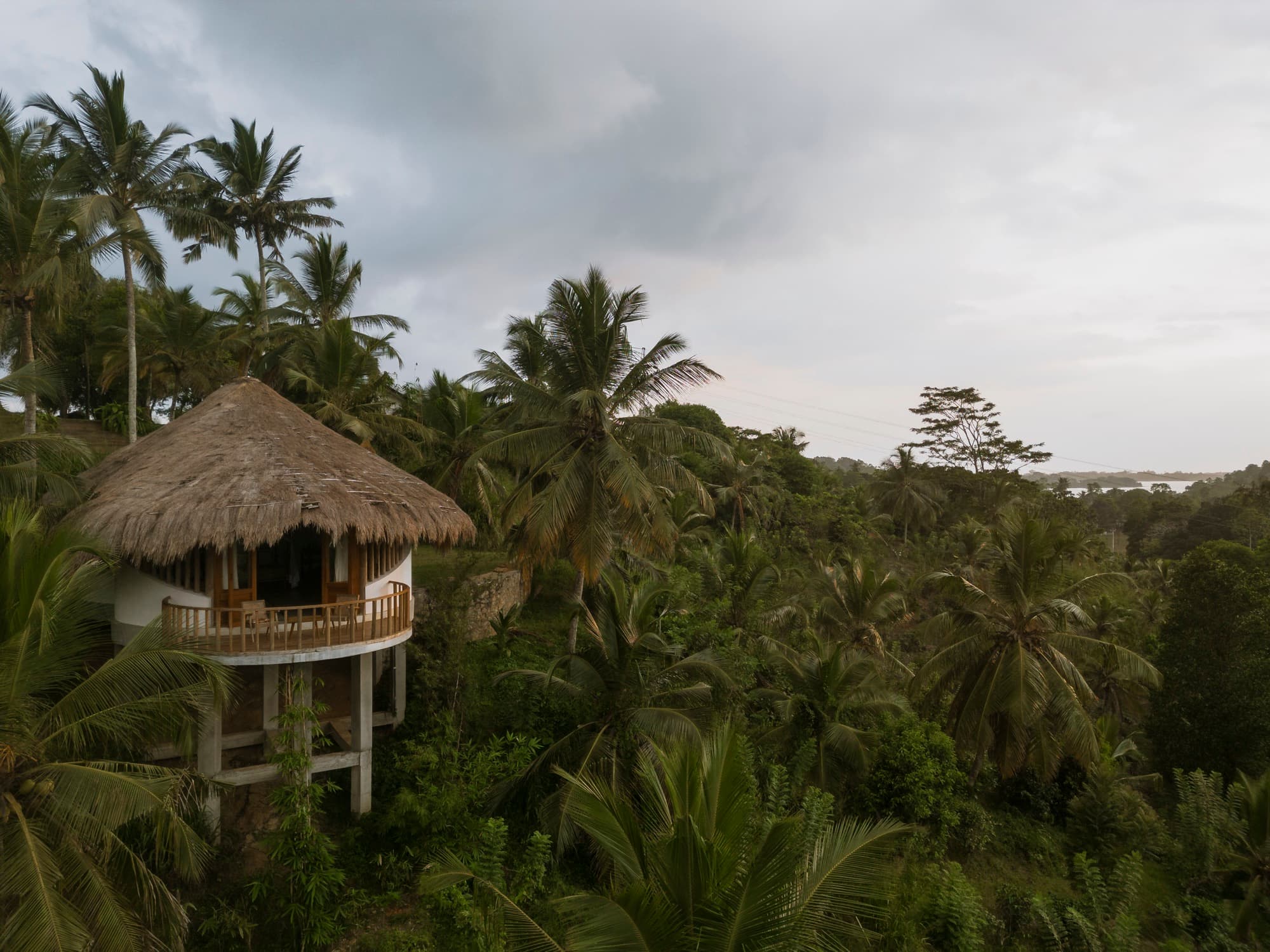 Aerial view of a round thatched cabana on stilts set in dense jungle near a lagoon — Tekanda Lodge, Ahangama