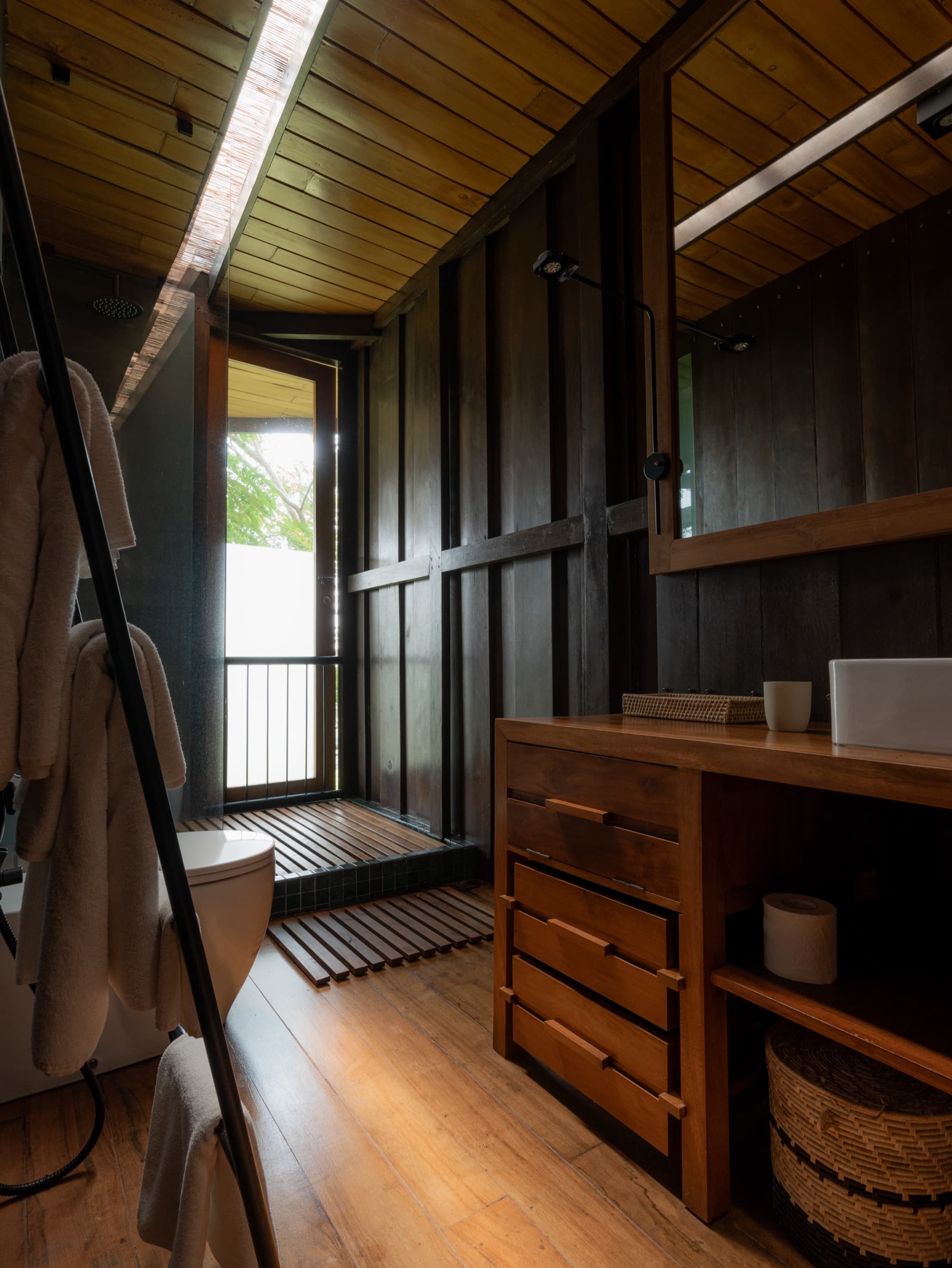 Timber bathroom with a stone vanity and a door opening to a private balcony
